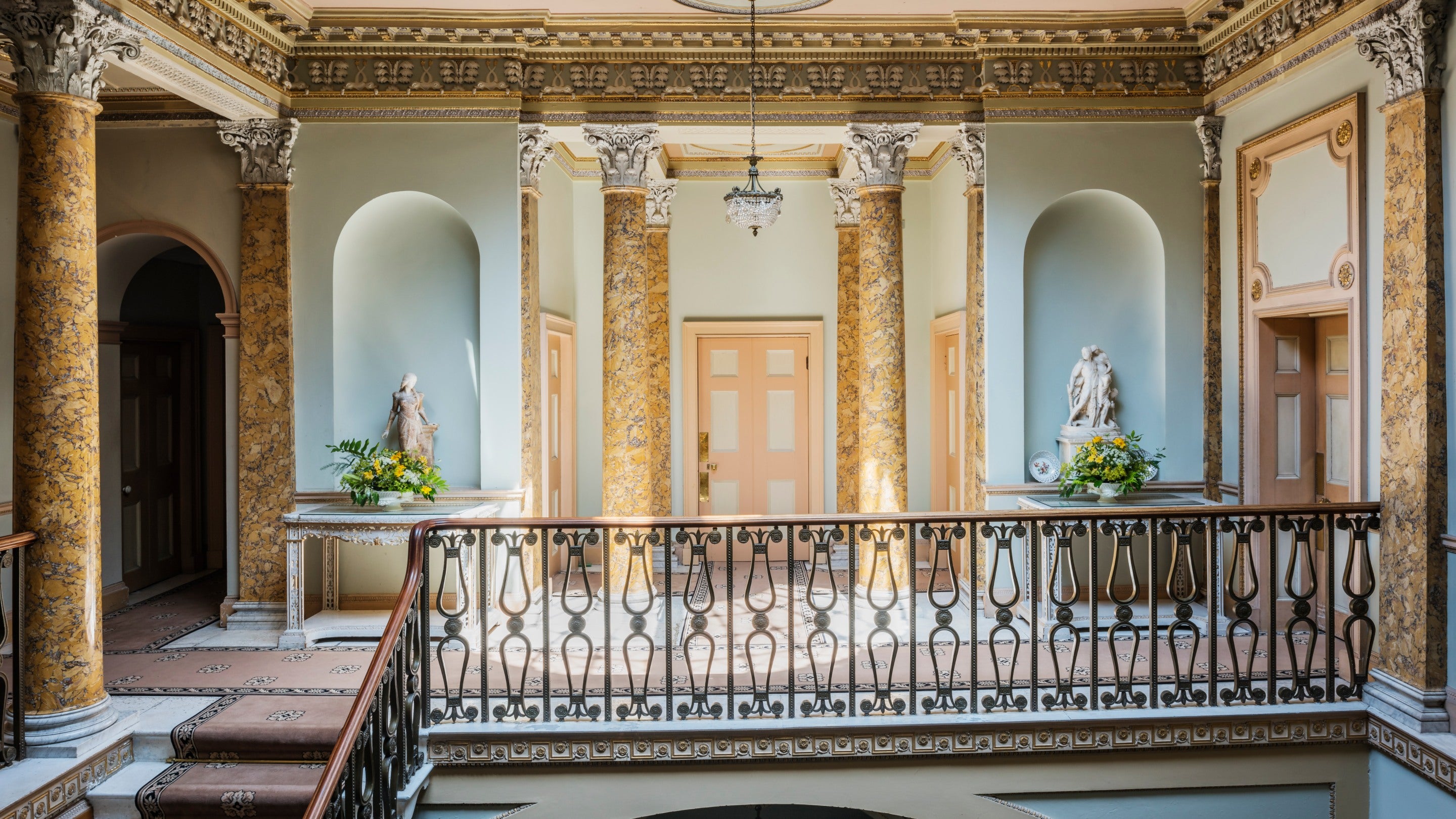 An interior view of the top of the Staircase Hall at Berrington Hall, Herefordshire, which has tall pillars and decorative plasterwork on the ceiling.