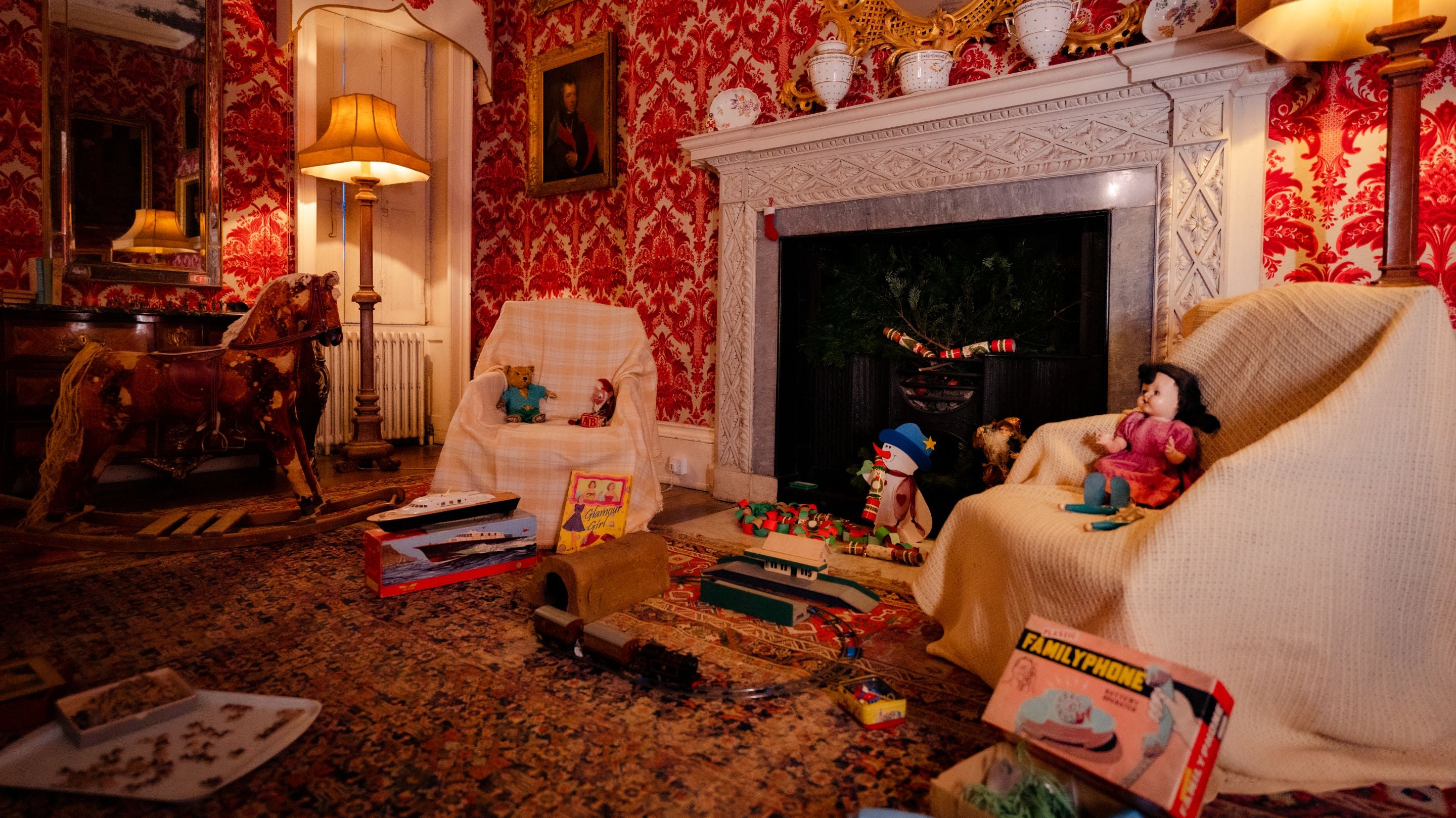 Vintage toys around a fire place, with rocking horse and small train set.