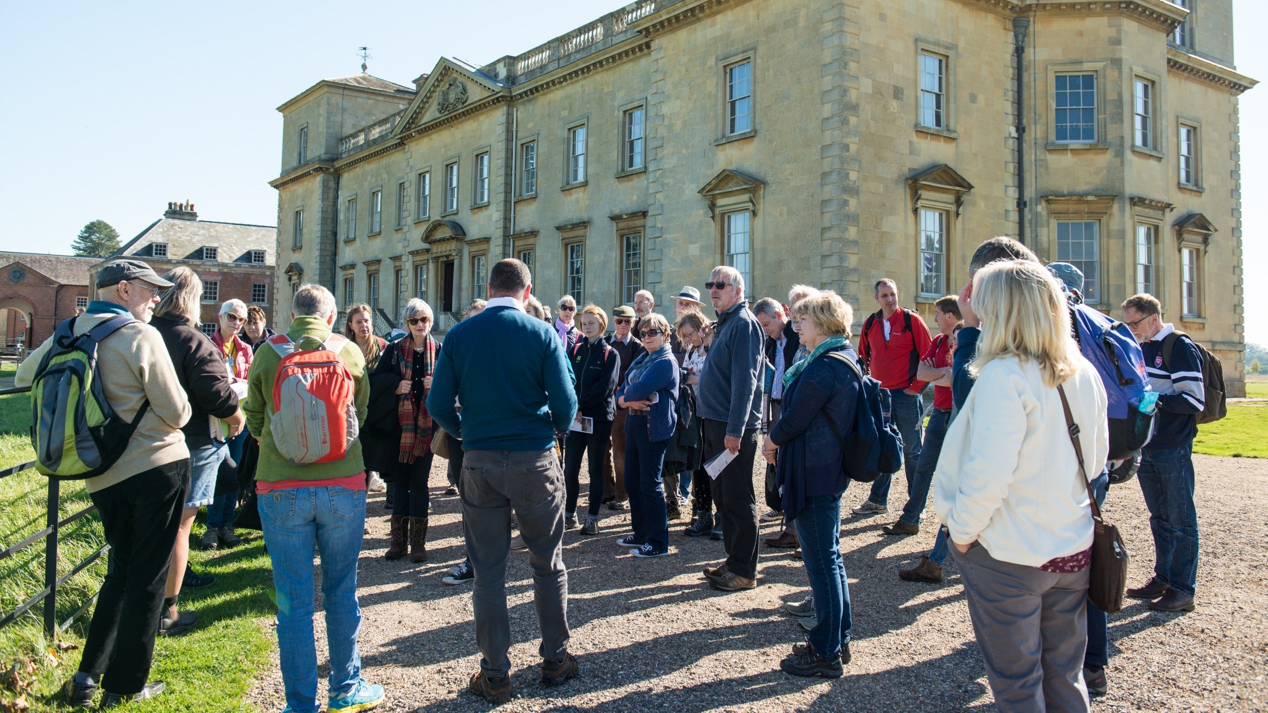 Large group of volunteers listening to guide in front of Croome House
