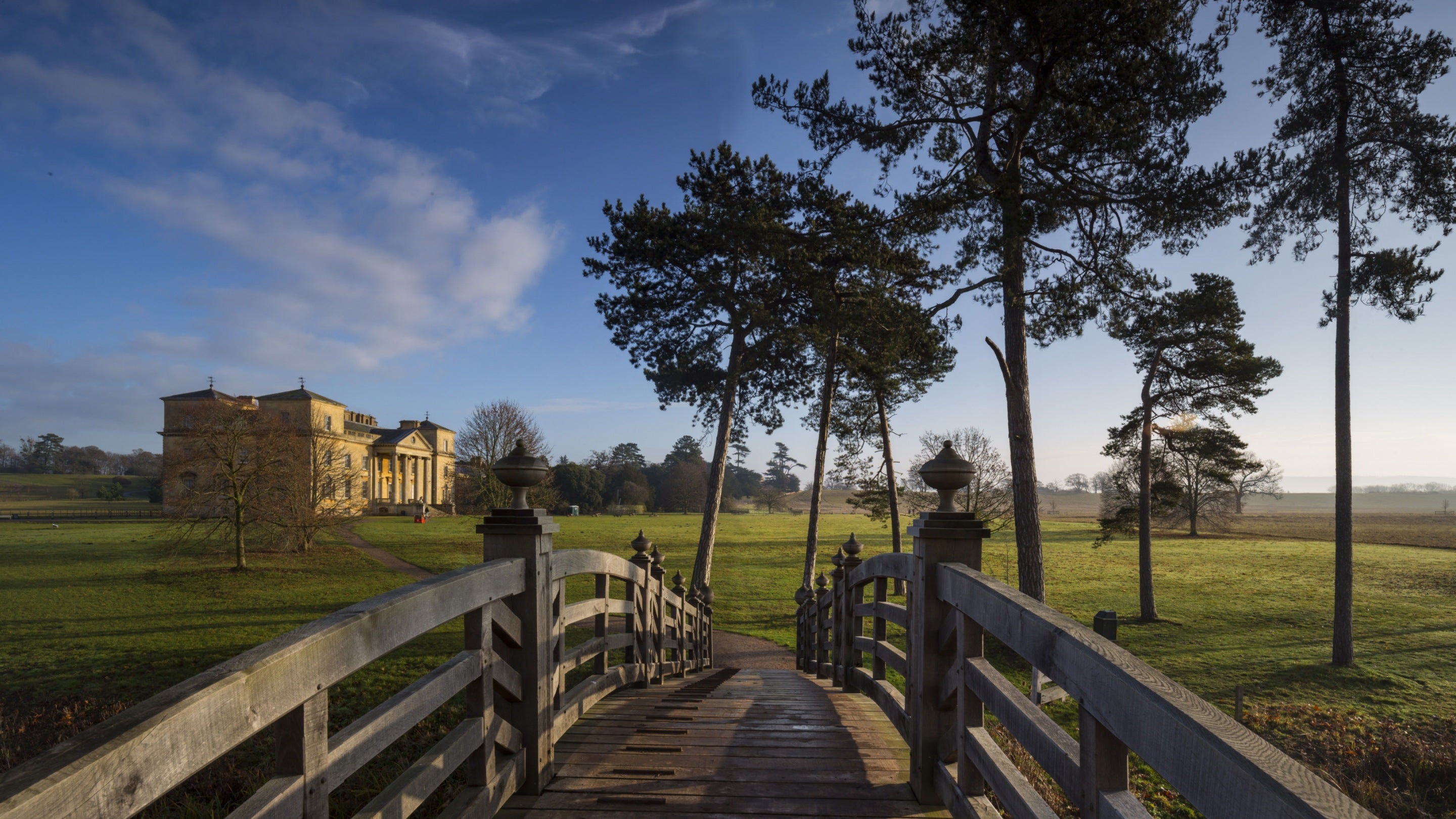 The Chinese Bridge over the river in the park with the Palladian mansion and trees in the background a at Croome, Worcestershire