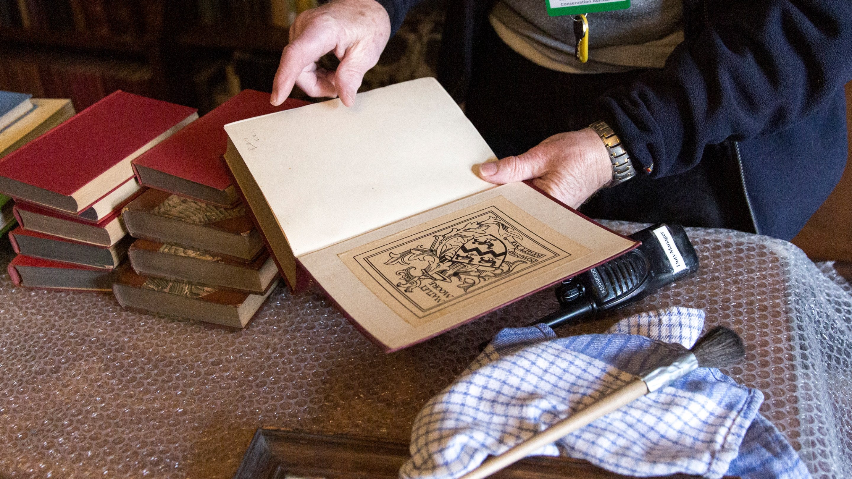 Volunteer examining a book as part of conservation work in the library at Greyfriars' House and Garden, Worcestershire