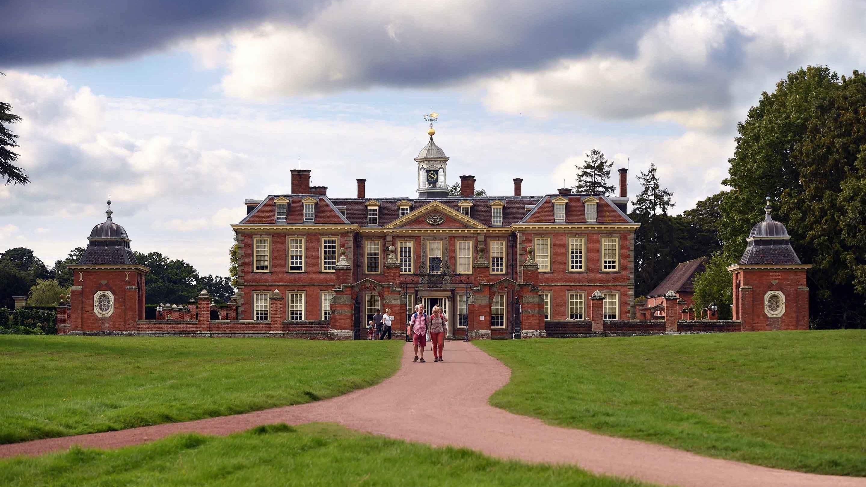 Visitors in the park on a path in front of the country house at Hanbury Hall and Gardens, Worcestershire