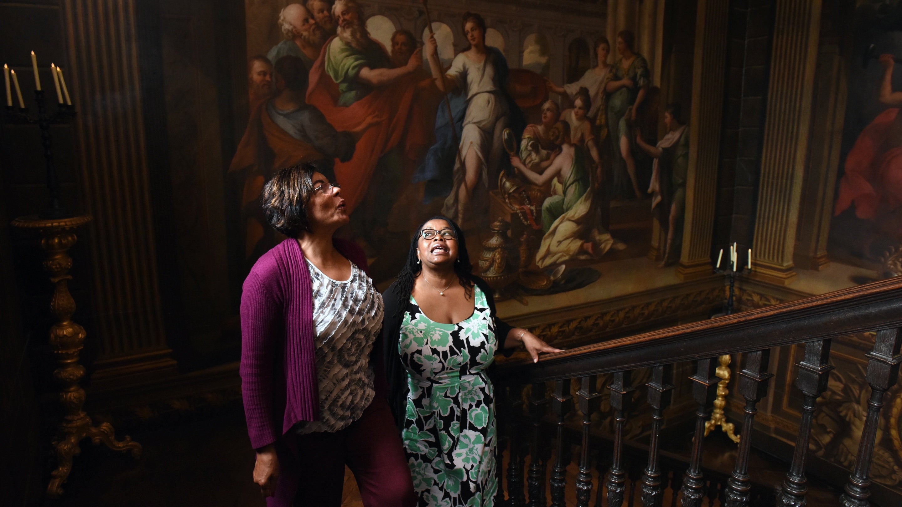 Two visitors walk up the staircase at Hanbury Hall, Worcestershire with the James Thornhill wall paintings seen behind.