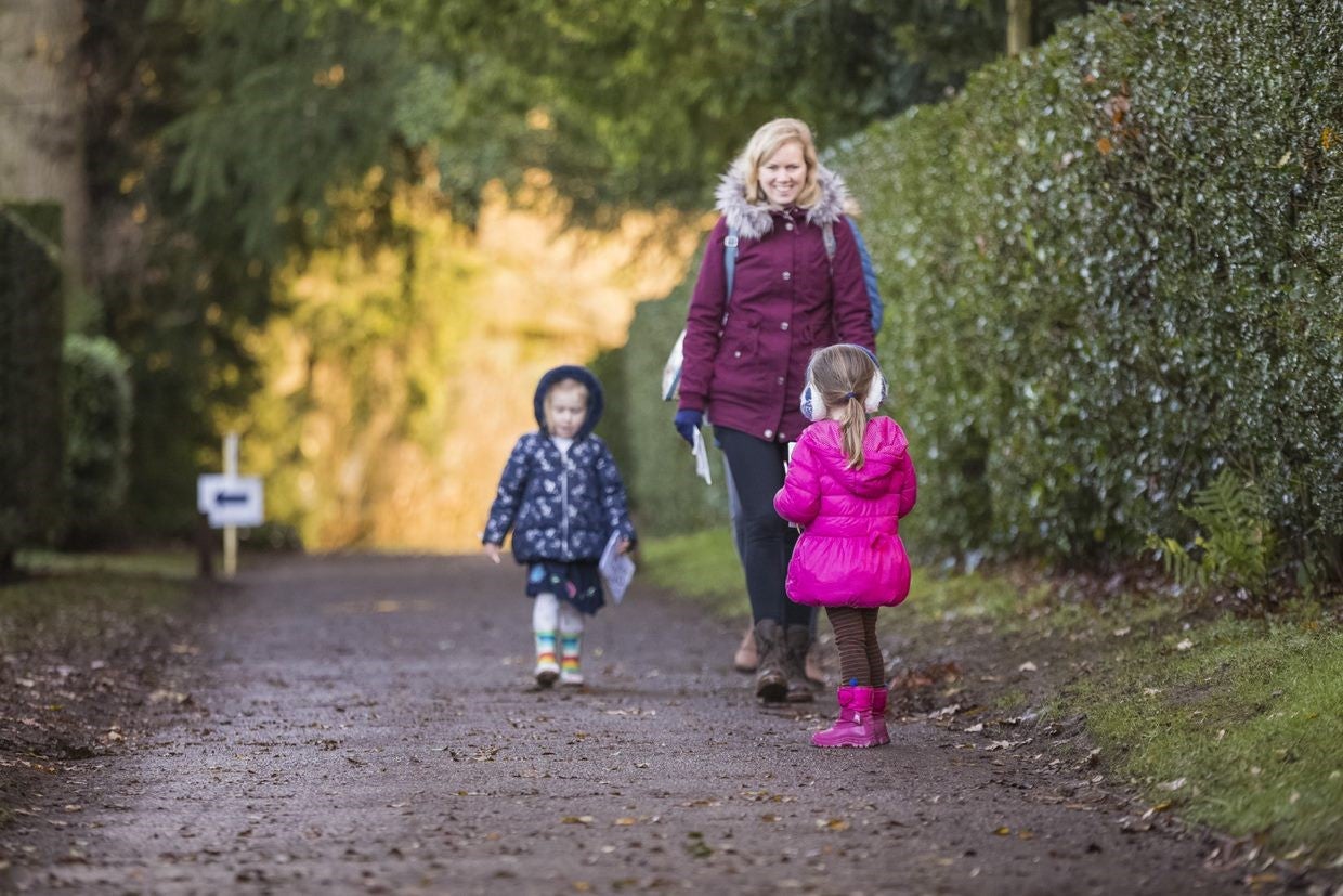 Two children and an adult walking down a path in the Hanbury Hall gardens