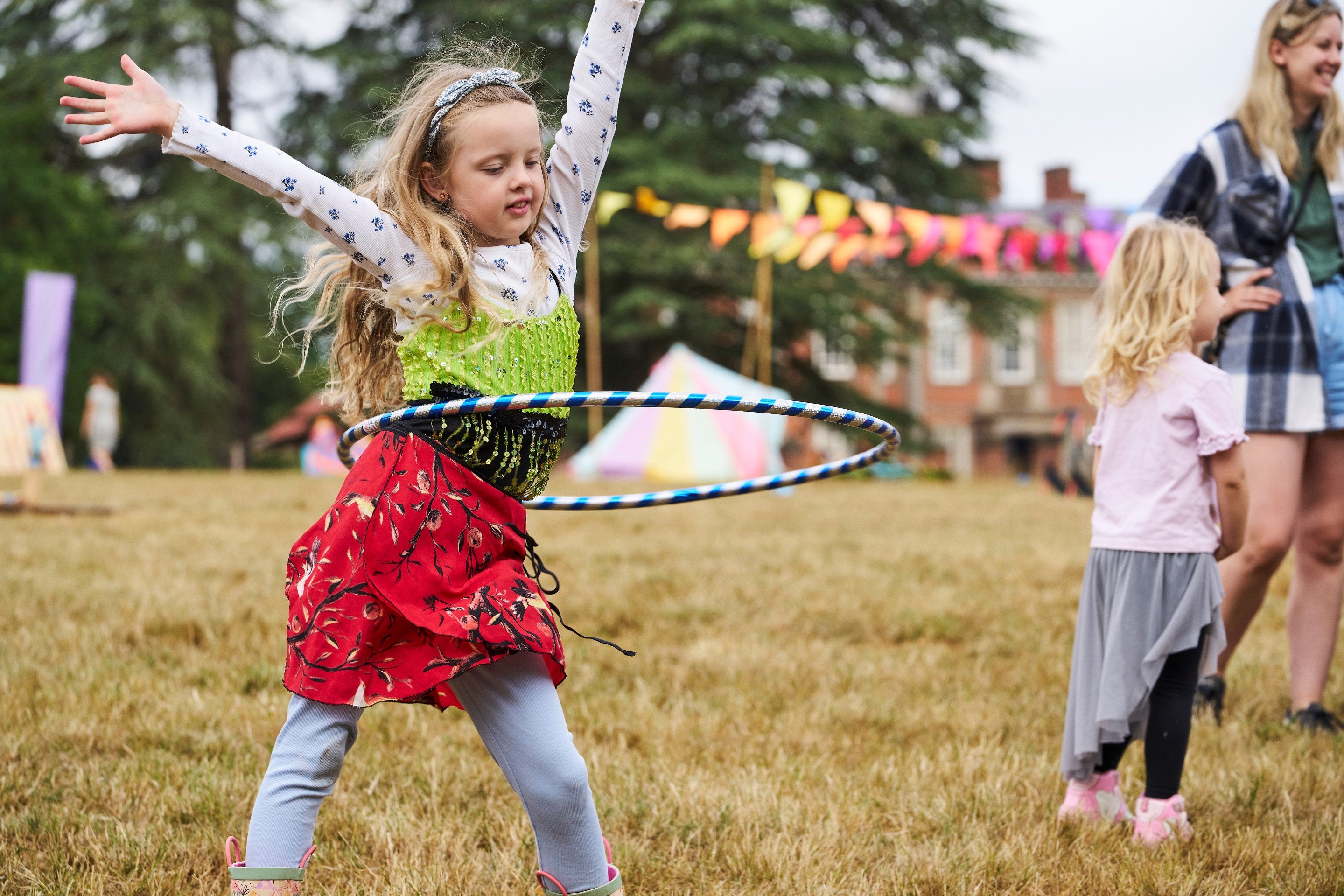A girl dancing with a hula hoop in the Summer of Play field at Hanbury Hall