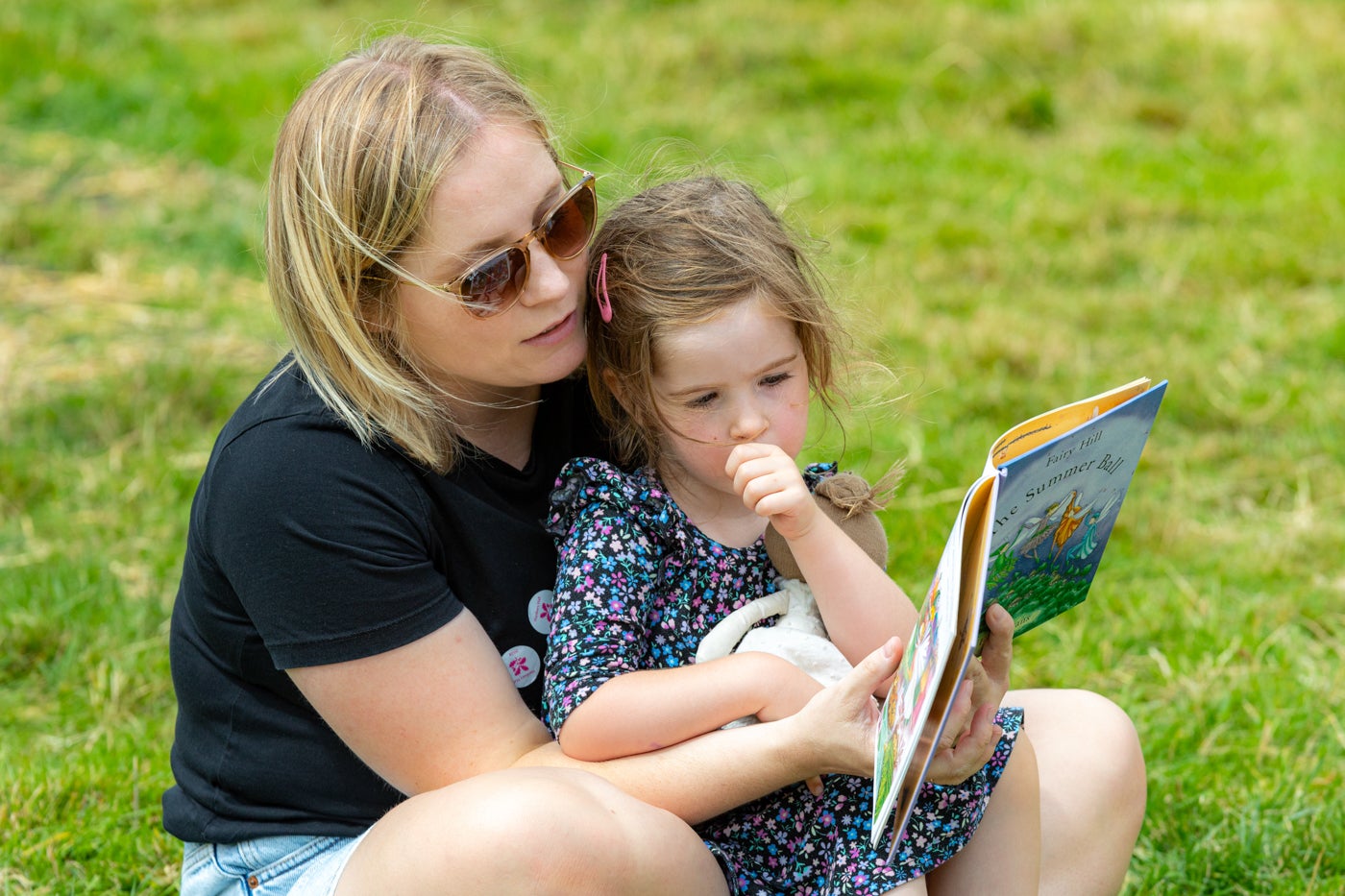 A lady and a young girl reading a story book in the gardens at Hanbury Hall