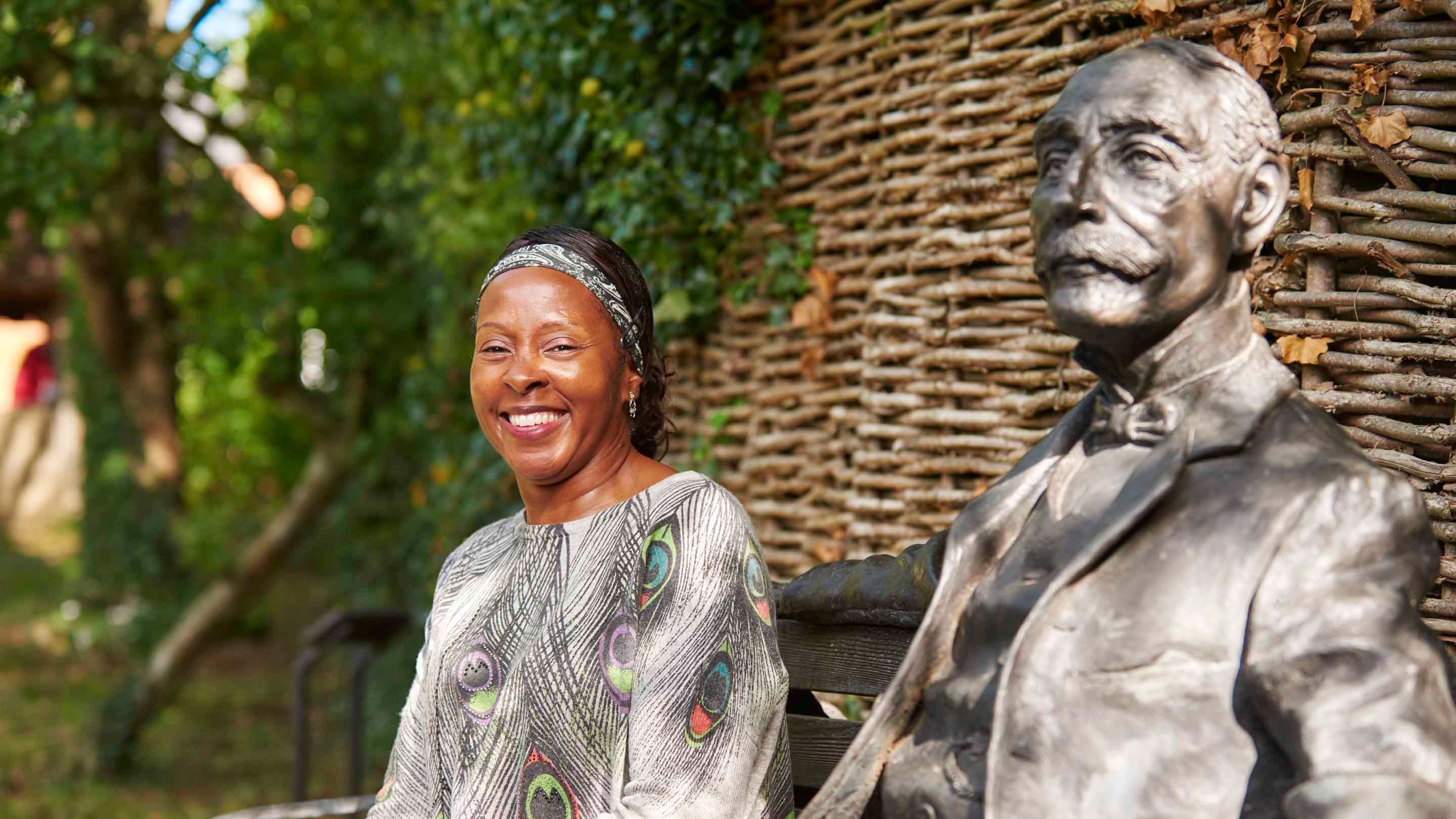 Visitor sat next to statue of Sir Edward Elgar gazing out to the Malvern Hills at The Firs, Worcestershire