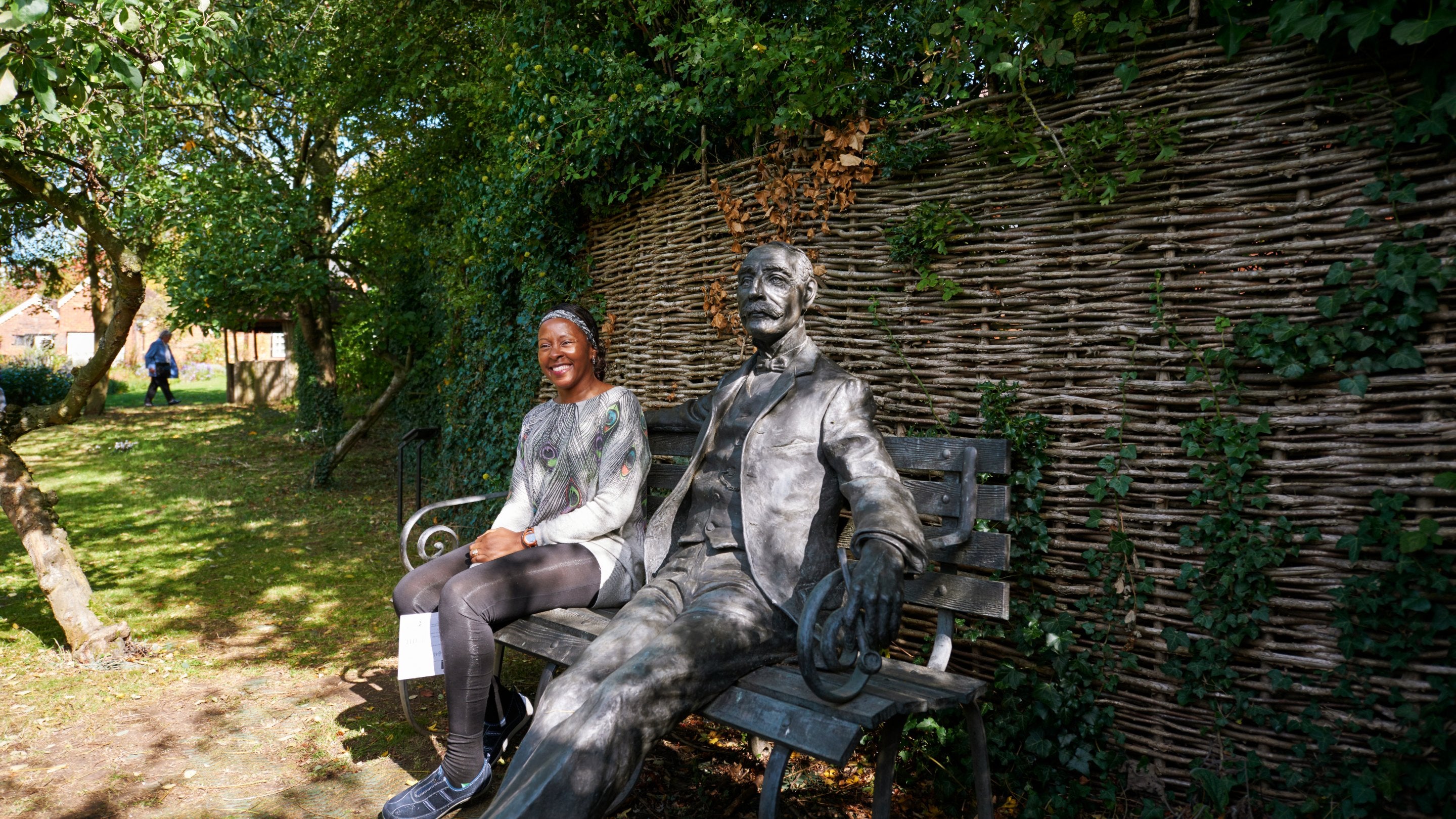 Visitor in the garden sitting next to statue of Edward Elgar at The Firs, Worcestershire