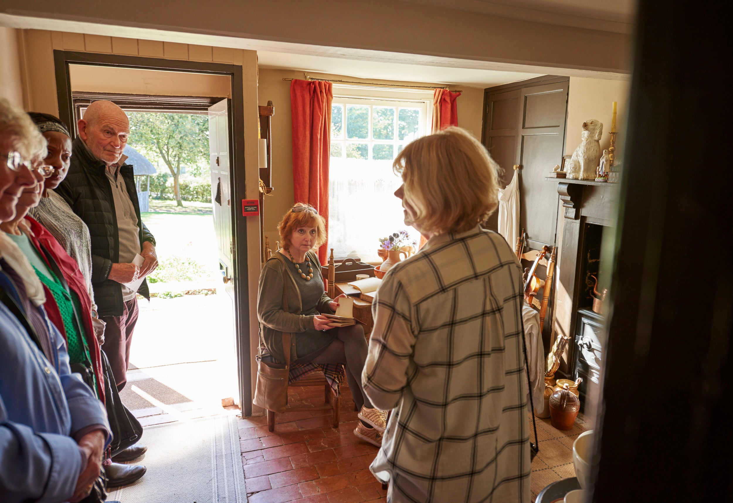 A group of visitors are standing in the Kitchen at The Firs while listening to a tour guide
