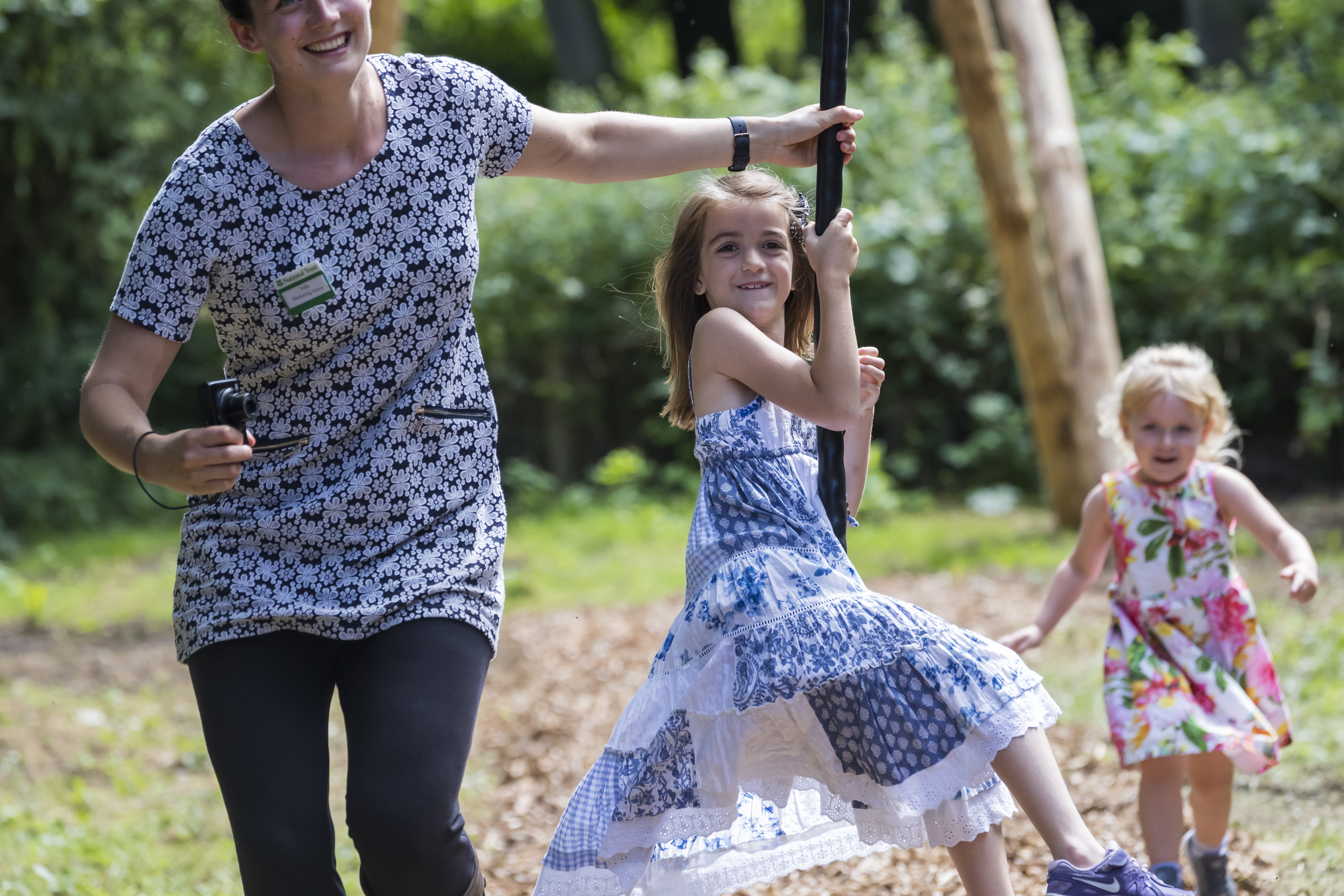 A girl sits on a zip wire which is pulled by a woman next to her