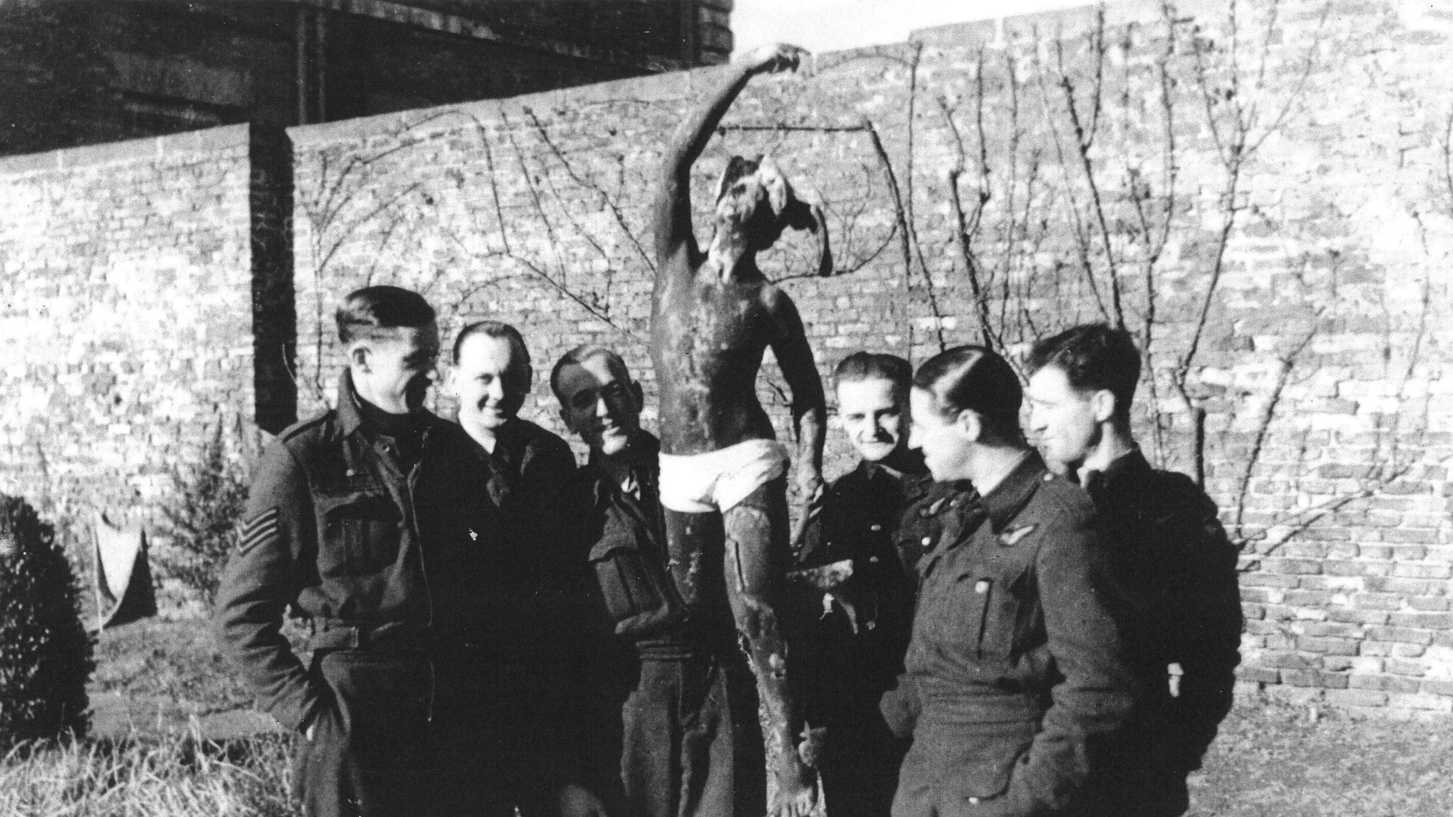 Black and white historic image showing airmen stood by a statue with white y-fronts on it