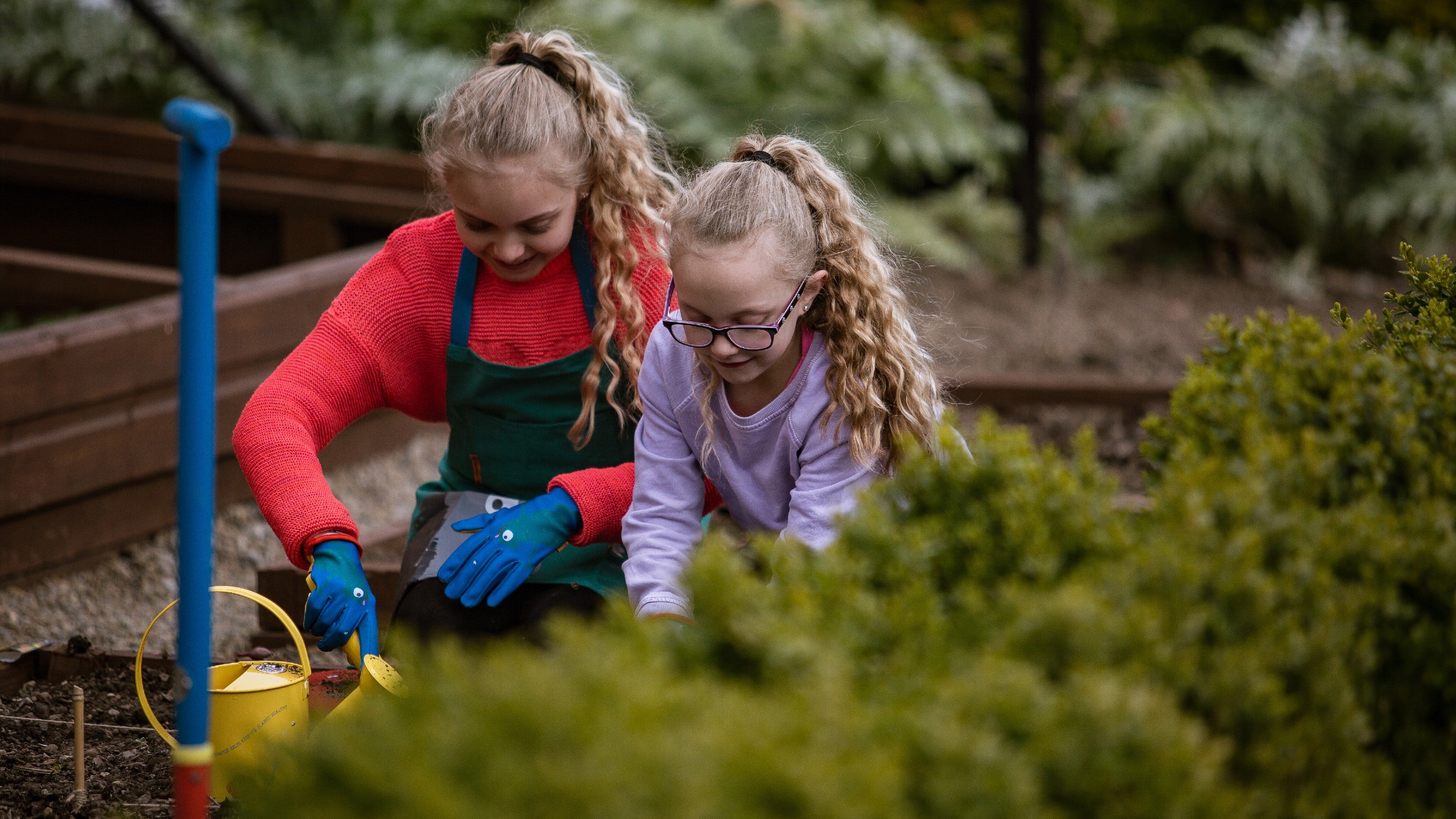 Two children gardening in a walled garden with small sized tools