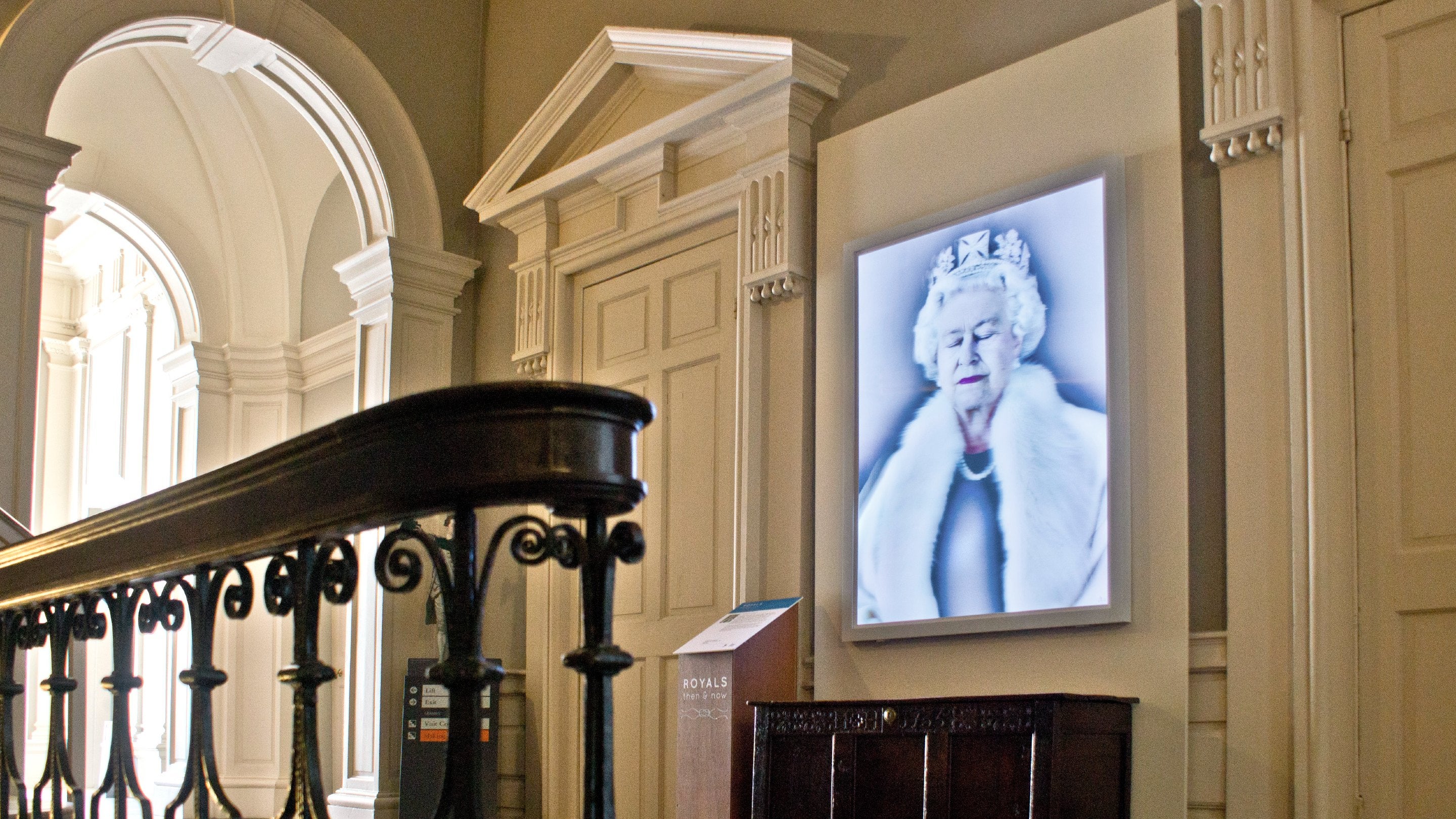 View showing a decorative staircase with a lit portrait of Queen Elizabeth II by Chris Levine