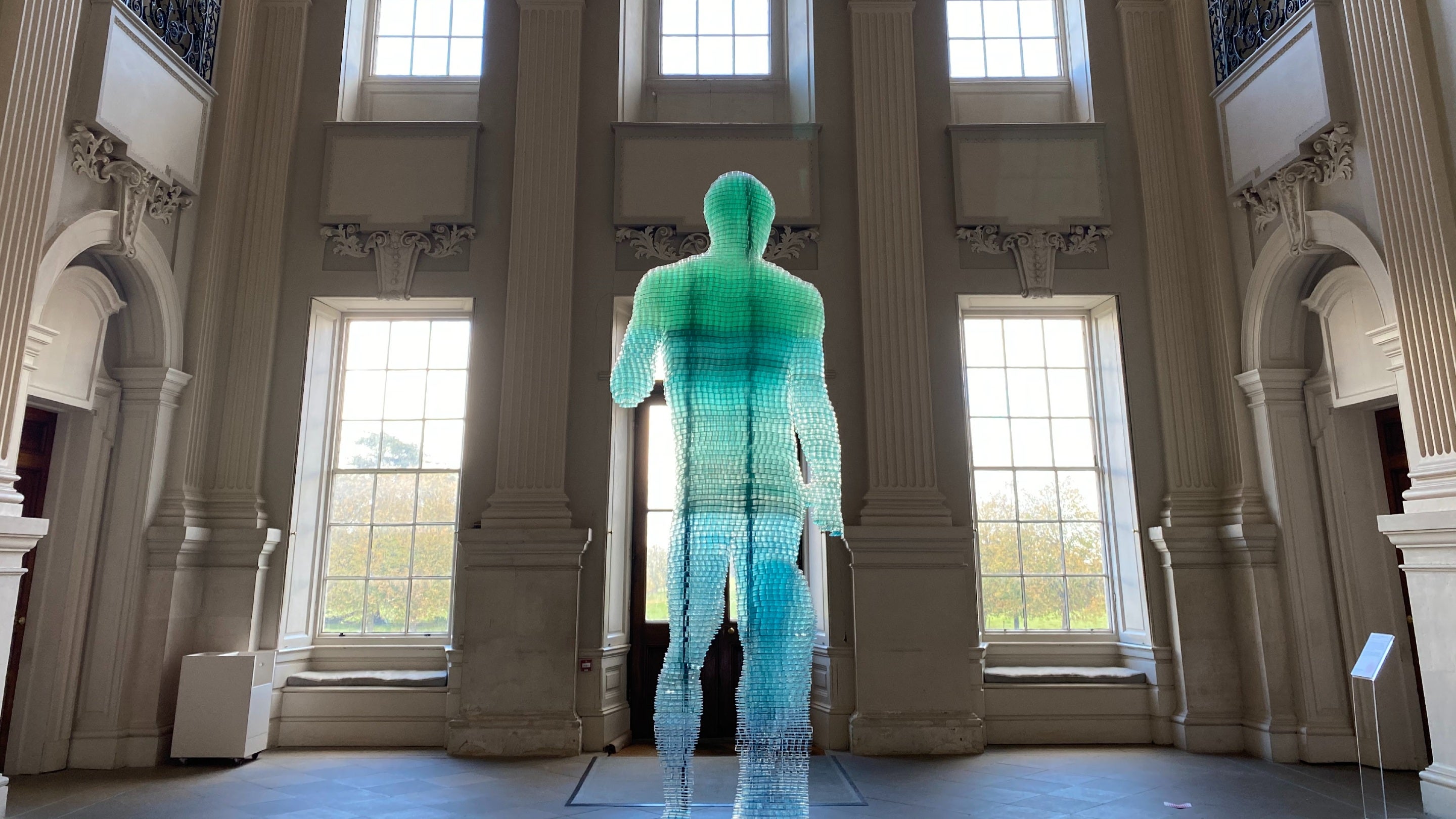 Modern sculpture of Doryphoros in a large historic hall with windows framing the artwork