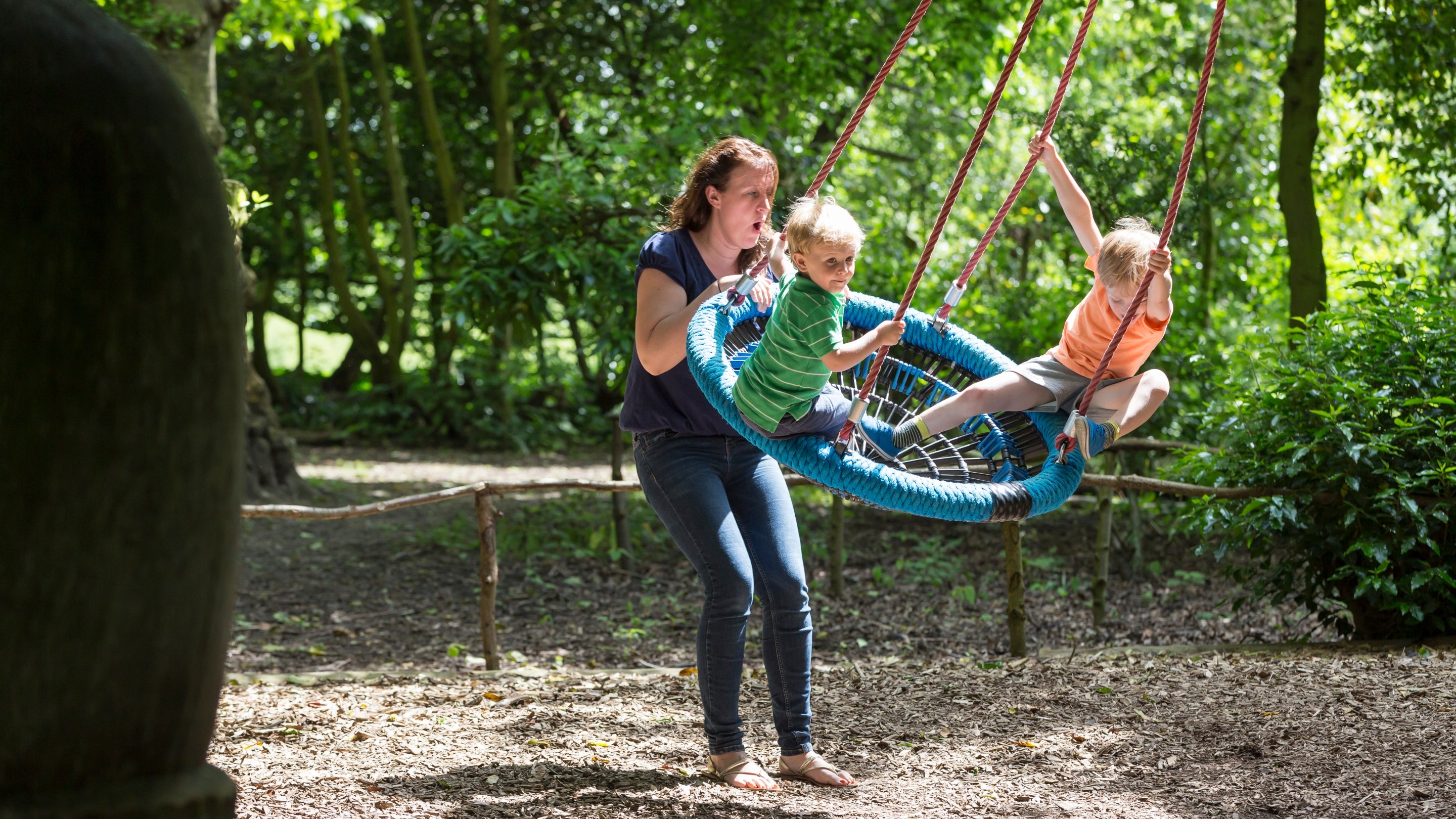 A woman pushes two children in the Queen swing in Beningbrough's play area