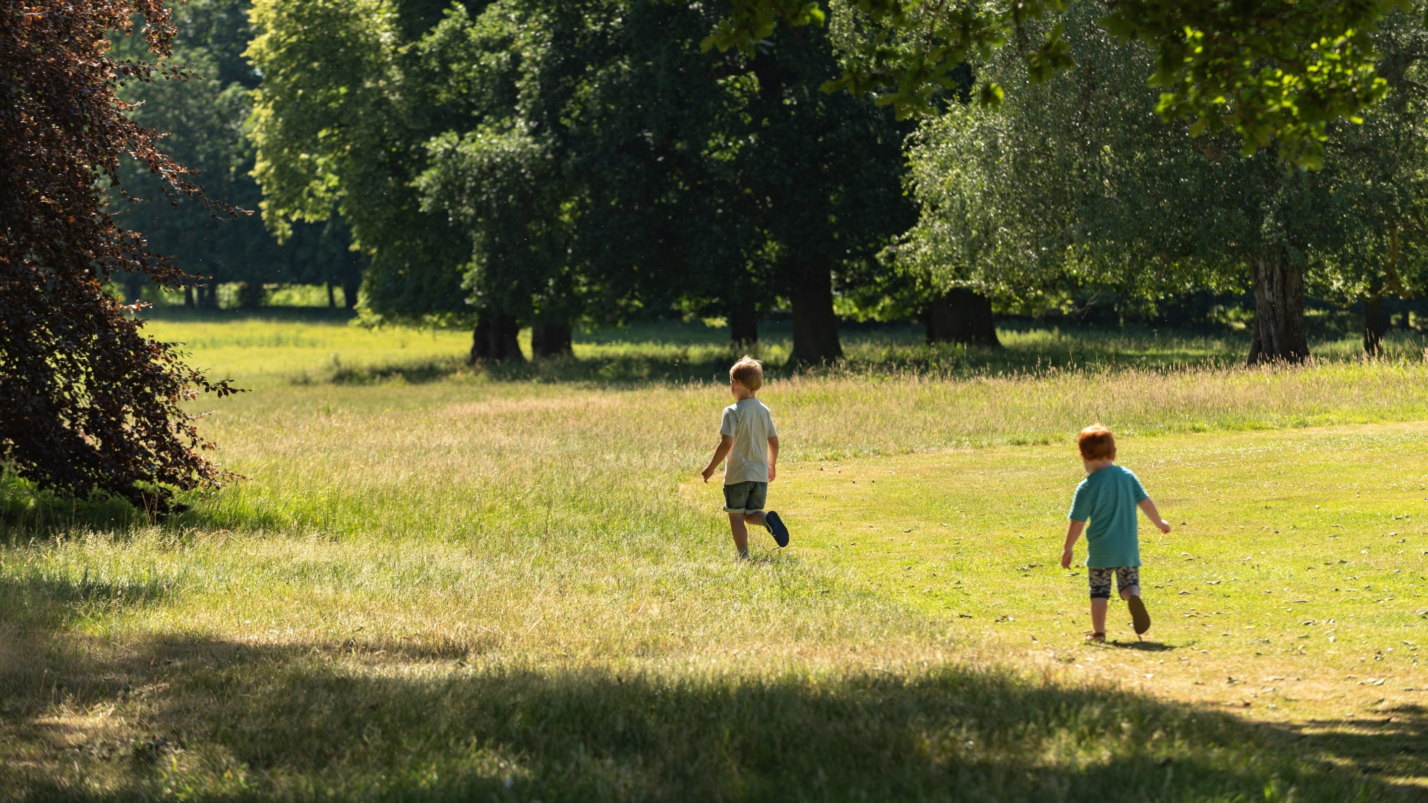 Two children running in the parkland at Beningbrough Hall, Yorkshire, on a sunny day