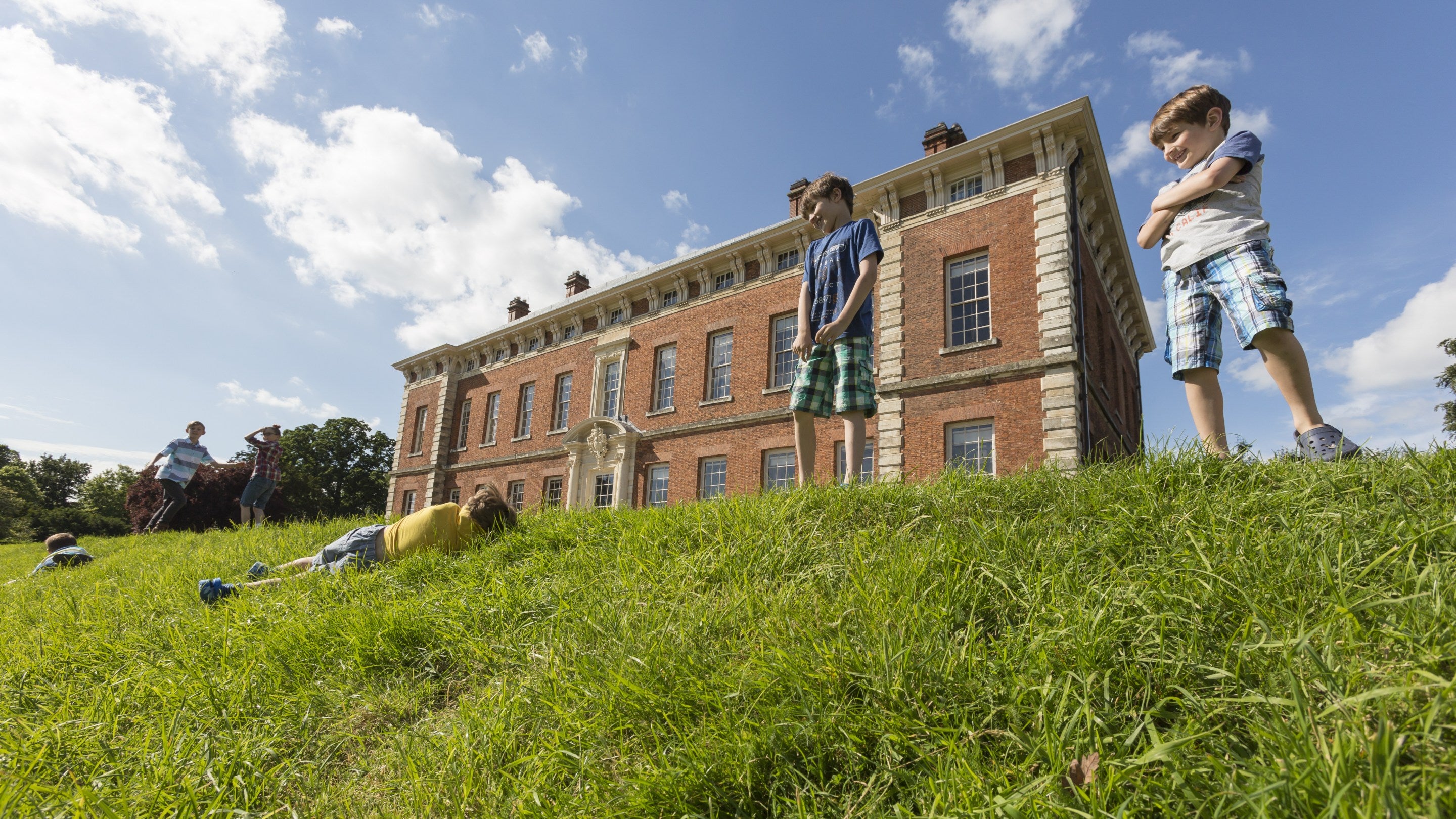 A young boy rolling down the bank in front of Beningbrough Hall, Gallery and Gardens, North Yorkshire