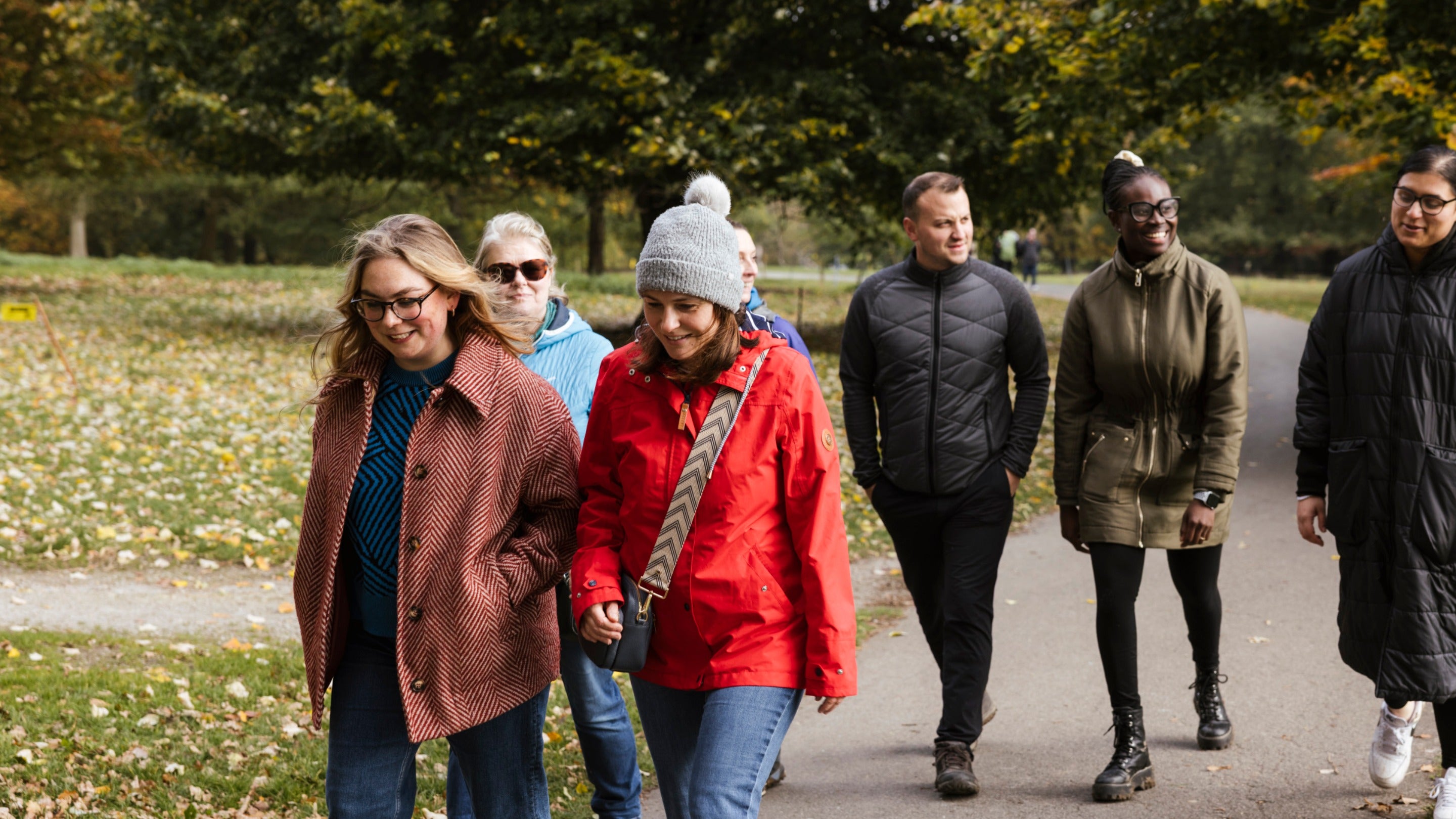 A group of adults walking together and wearing coats and hats on a winters day