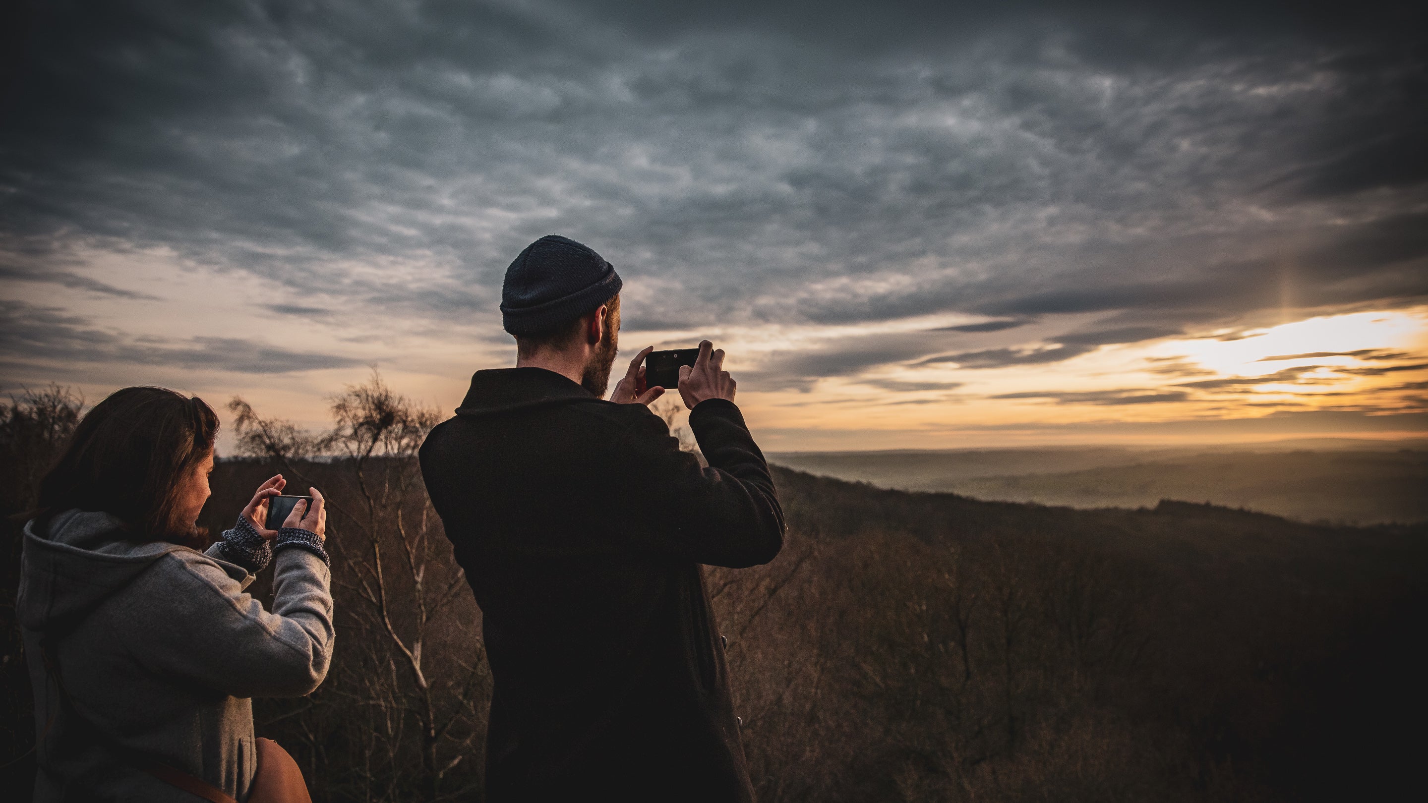 A couple snap some photos of the sun setting at Brimham Rocks in the low winter light.