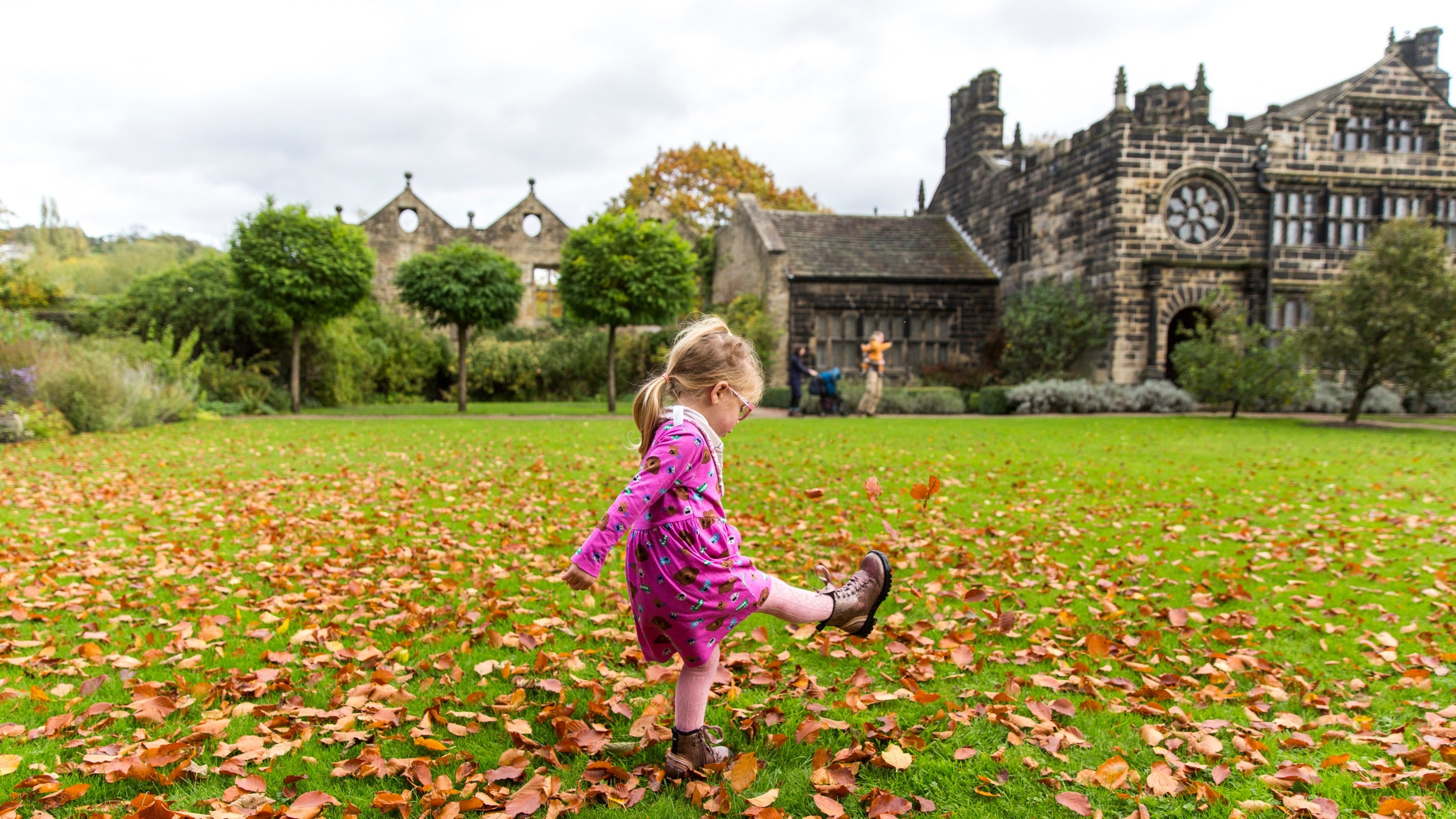 Girl playing in autumn leaves at East Riddlesden Hall, West Yorkshire