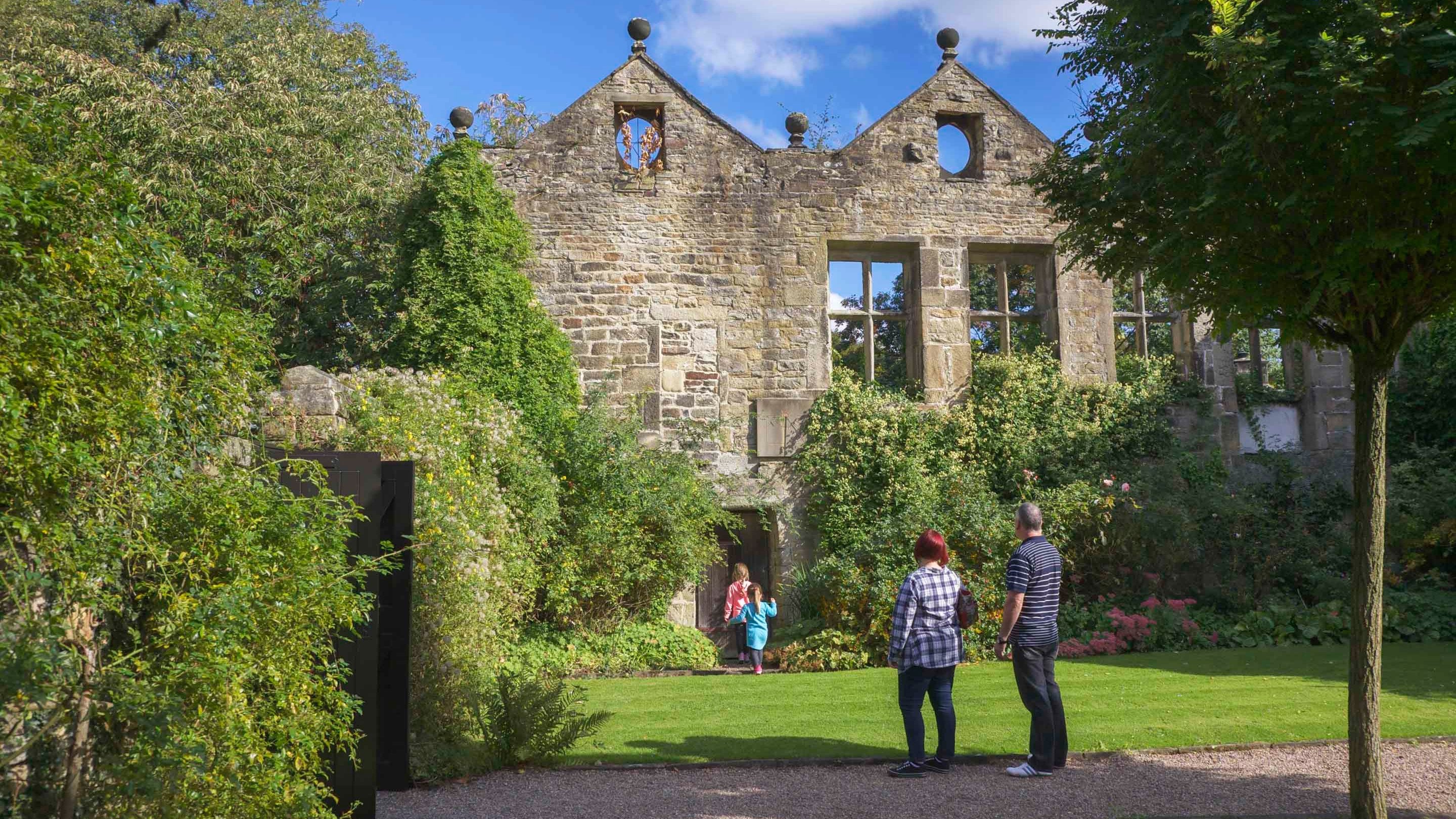 Two adults and two children in the garden at East Riddlesden Hall