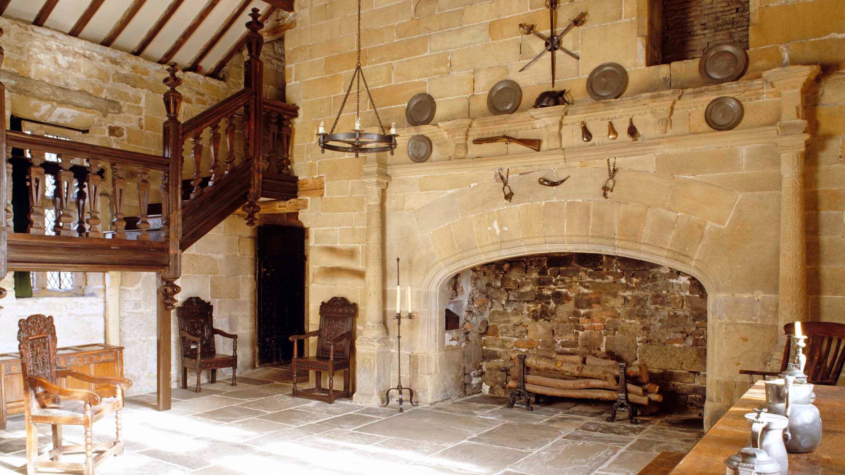 The Hall showing the fireplace and part of the staircase at East Riddlesden Hall, West Yorkshire. The fireplace is decorated with thistles and terminal heads, and forms a structural part of the 1640s rebuilding of the east range. The oak furniture is early to mid-seventeenth century.