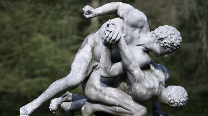 Lead sculpture on a stone plinth, The Wrestlers by Andrew Carpenter (c.1677 - London 1737), 1730. One man pins down the other, who is on his knees with his head lowered and one arm held behind his back by the other man.