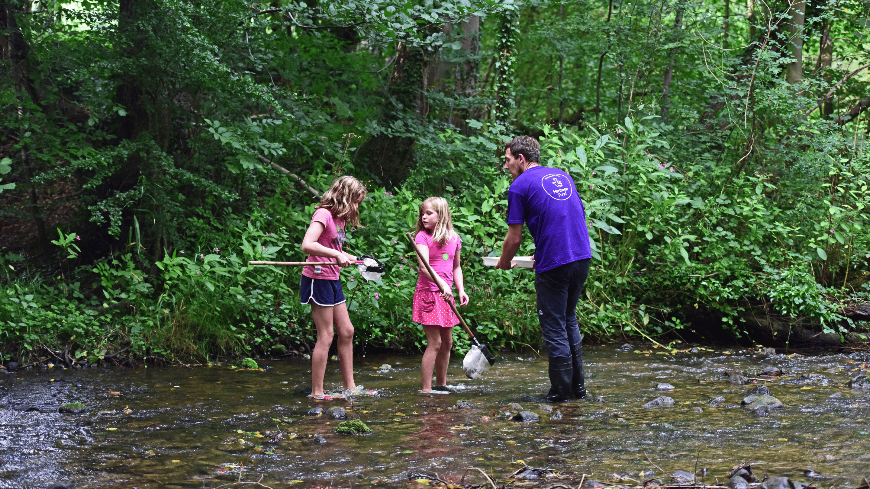 The photo shows two girls river dipping with an adult