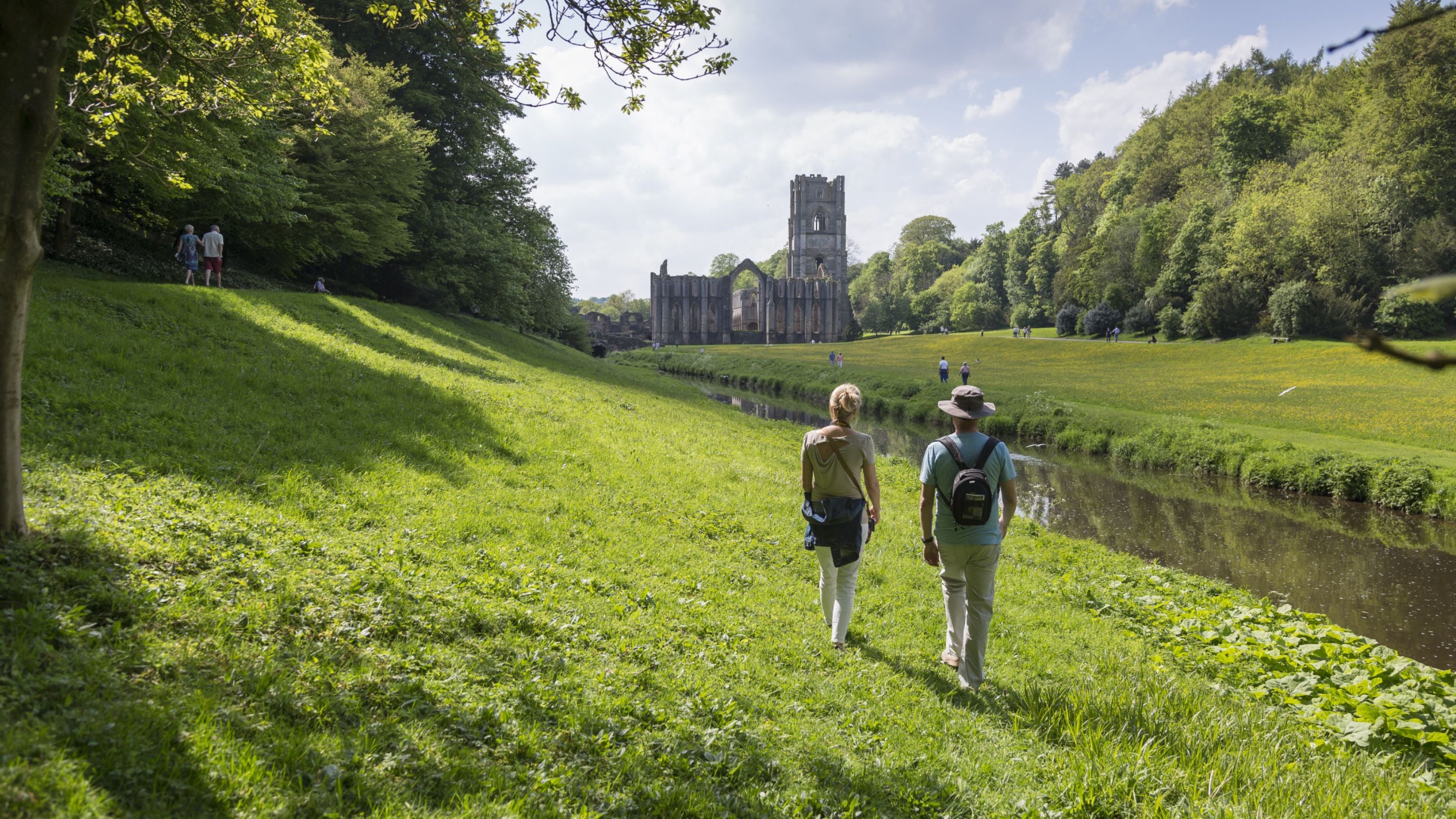 Two visitors walk through the grounds of Fountains Abbey, North Yorkshire