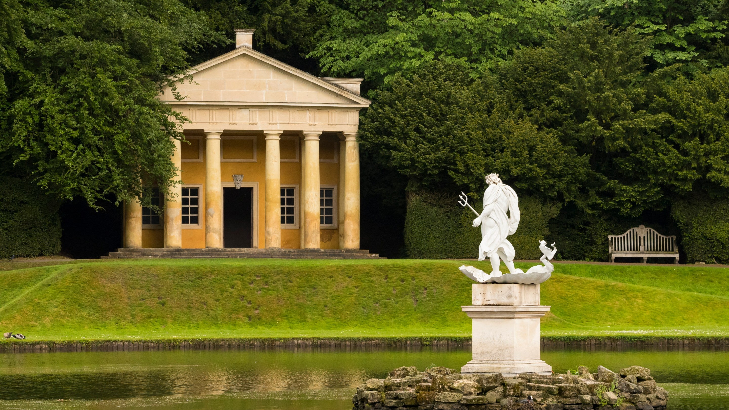 The statue of Neptune with the Temple of Piety in the background at Fountains Abbey and Studley Royal Water Garden, Yorkshire
