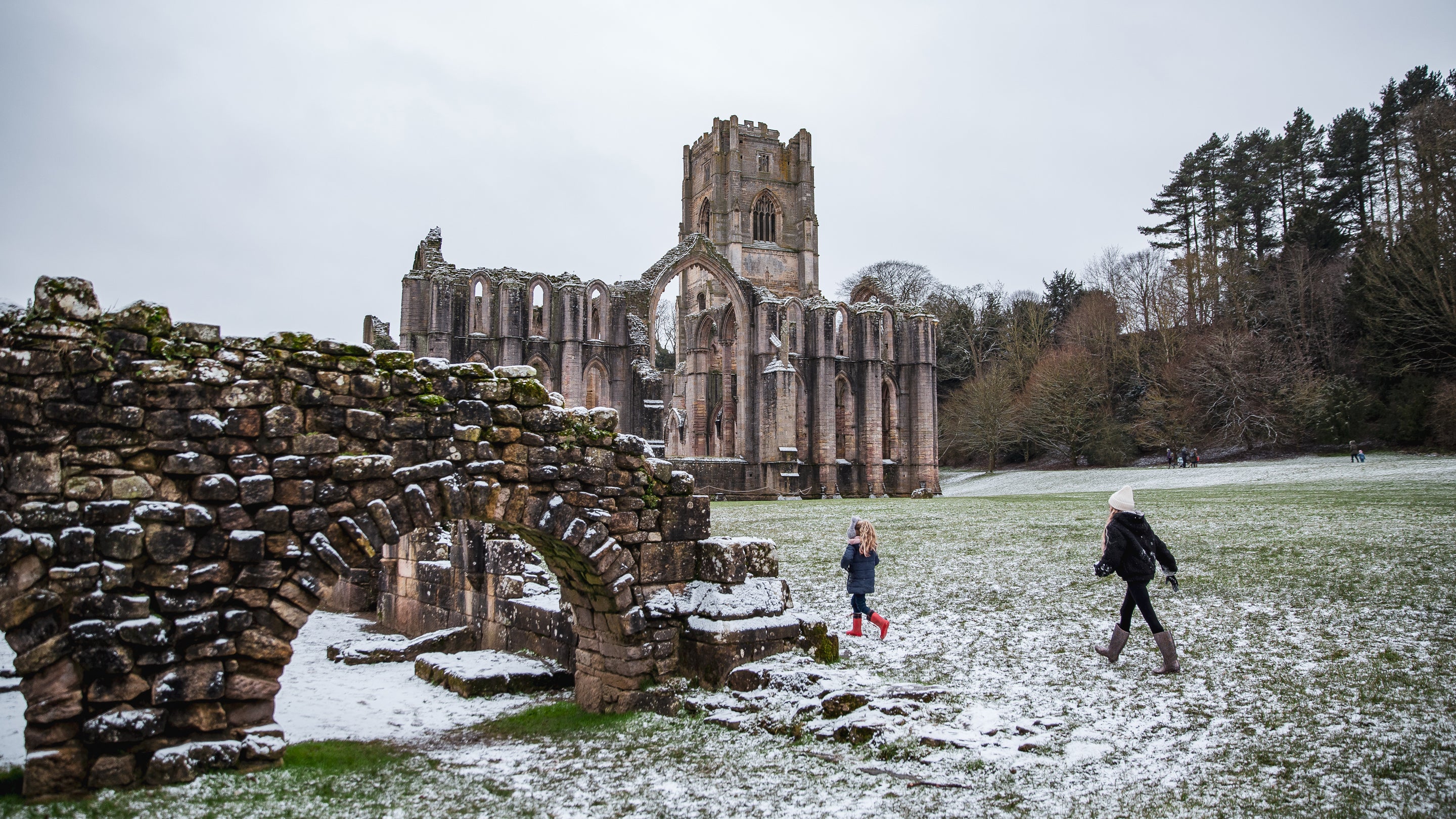 Children walking in a dusting of snow at Fountains Abbey