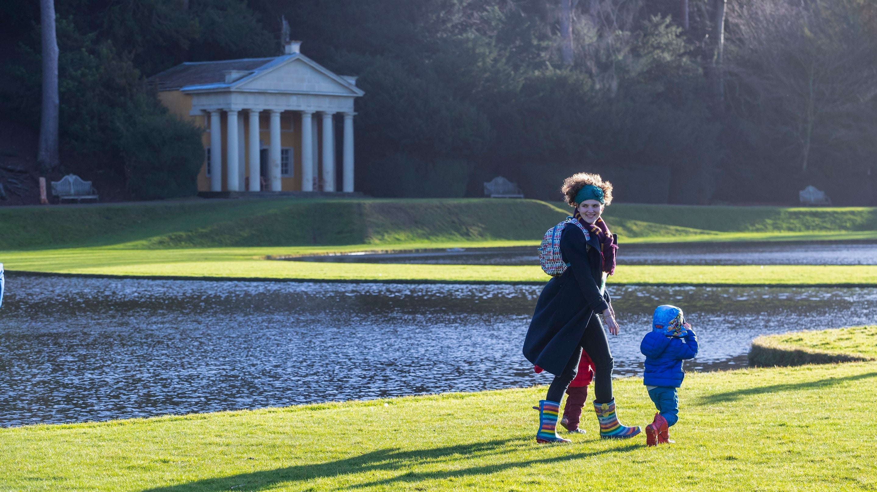 A family walks in the parkland at Studley Royal Water Garden in bright winter sun