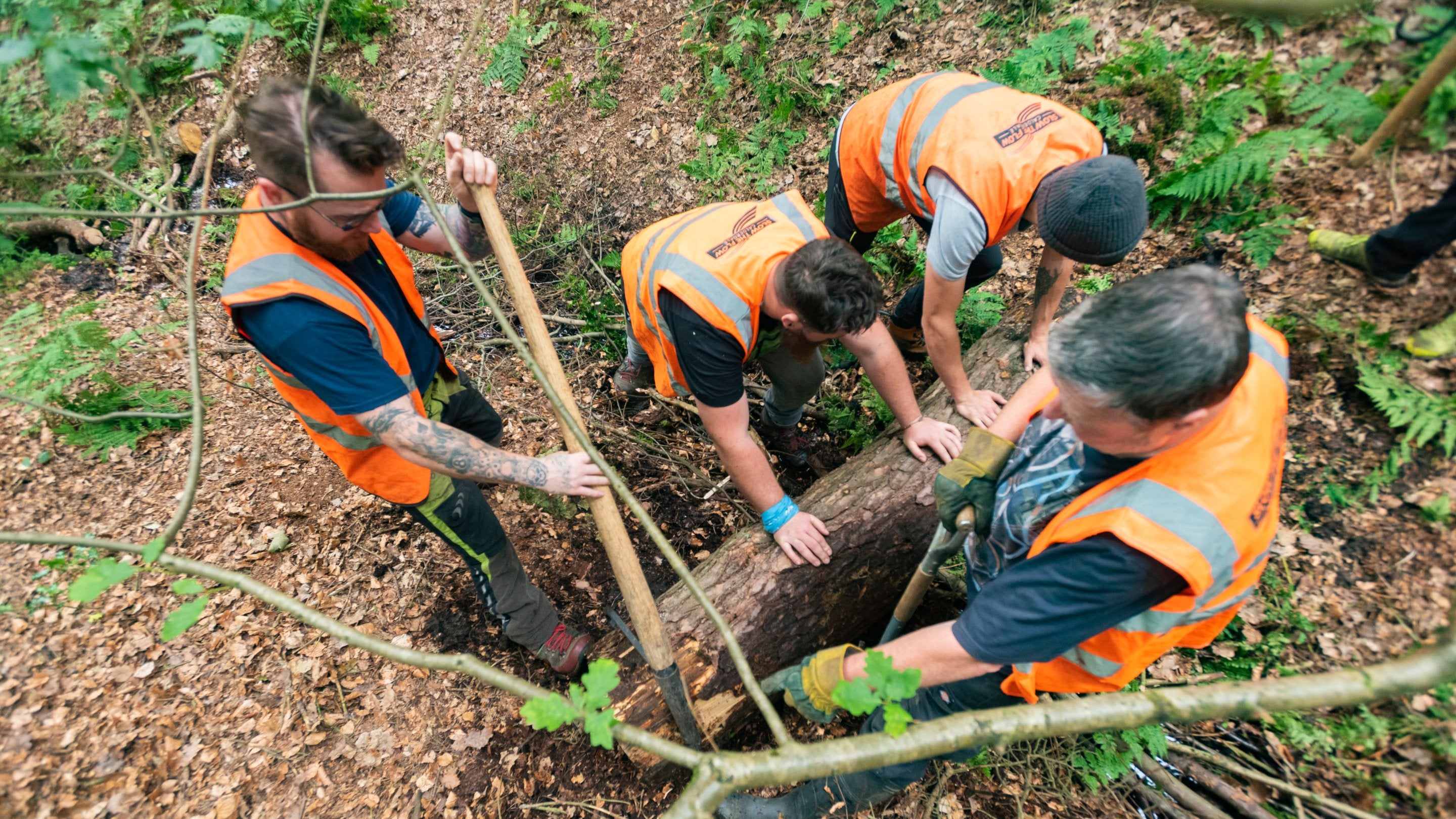 Top down shot of four volunteers rolling a log at Hardcastle Crags, Yorkshire