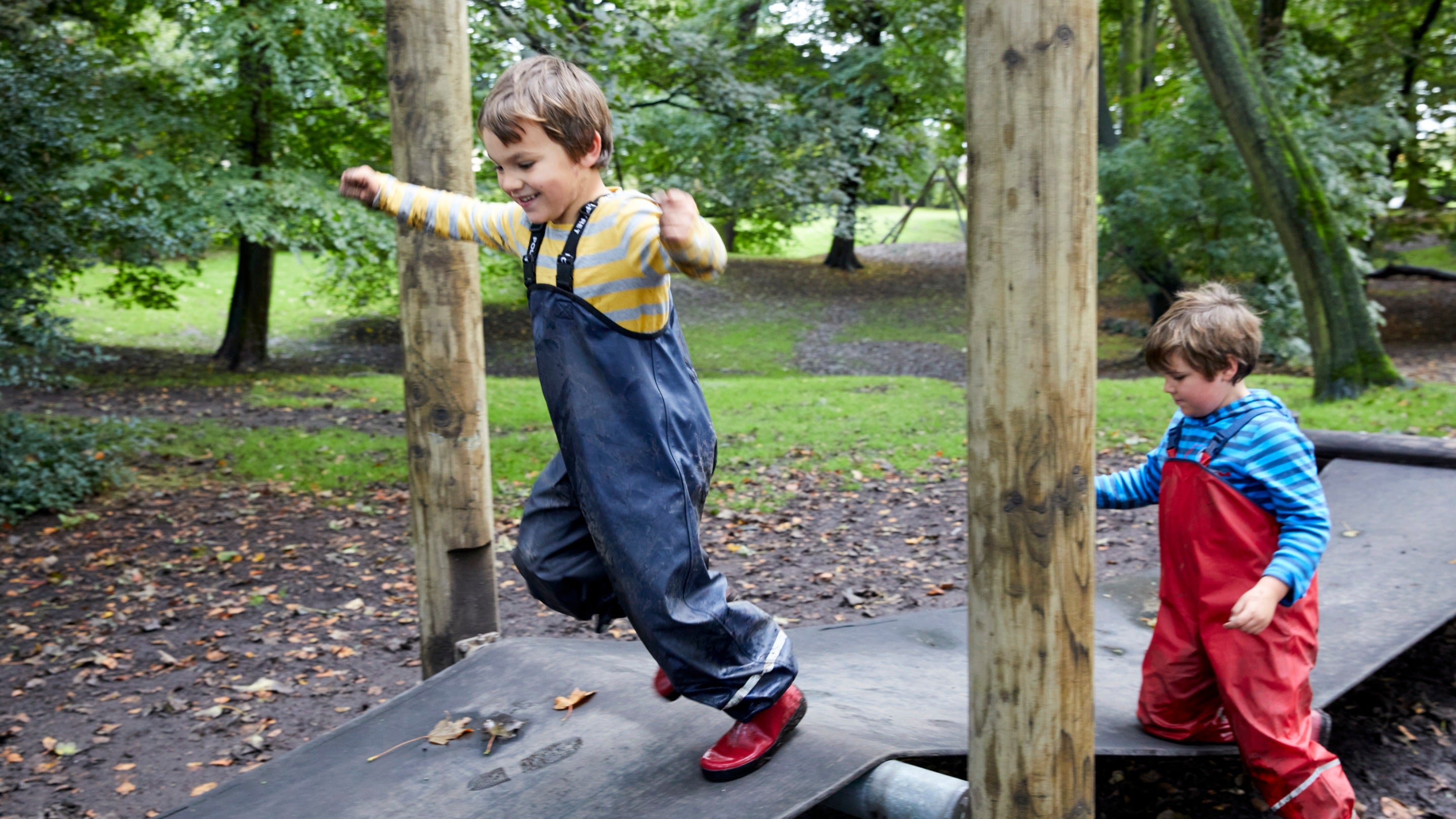 Two children running on a wobble bridge in the play area at Nostell in Autumn