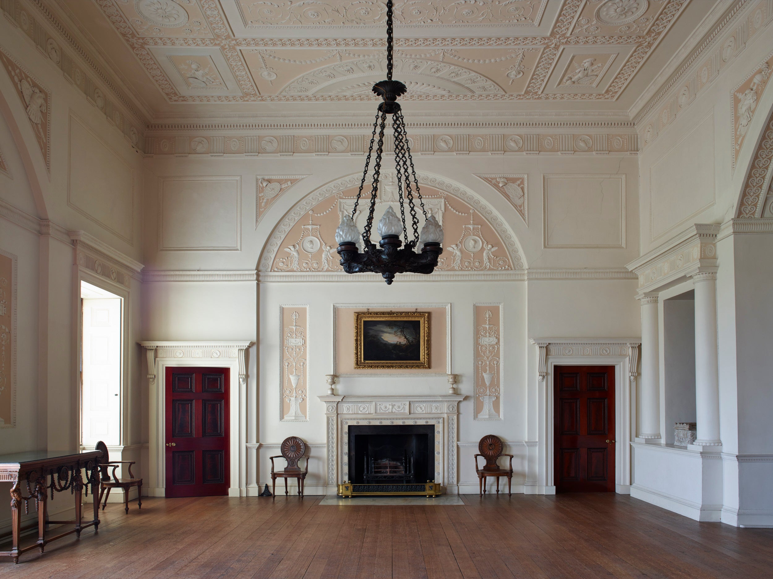 Interior of the Top Hall at Nostell Priory, showing a high ceiling, chandelier, wooden floor and fireplace.