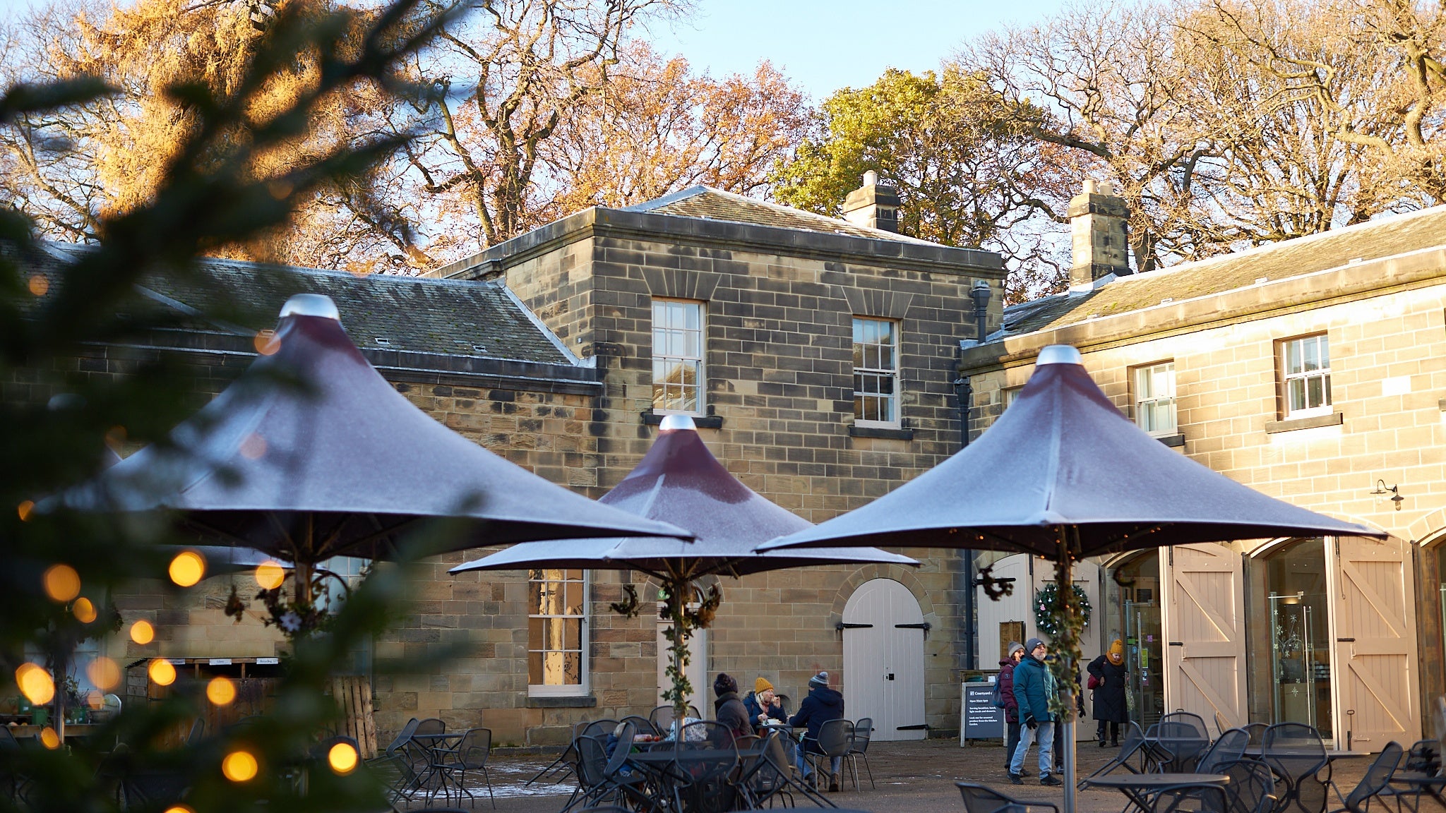 The stables courtyard at Nostell decorated for Christmas with visitors in the background