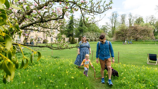 Young family walking through the meadows in spring at Nunnington Hall