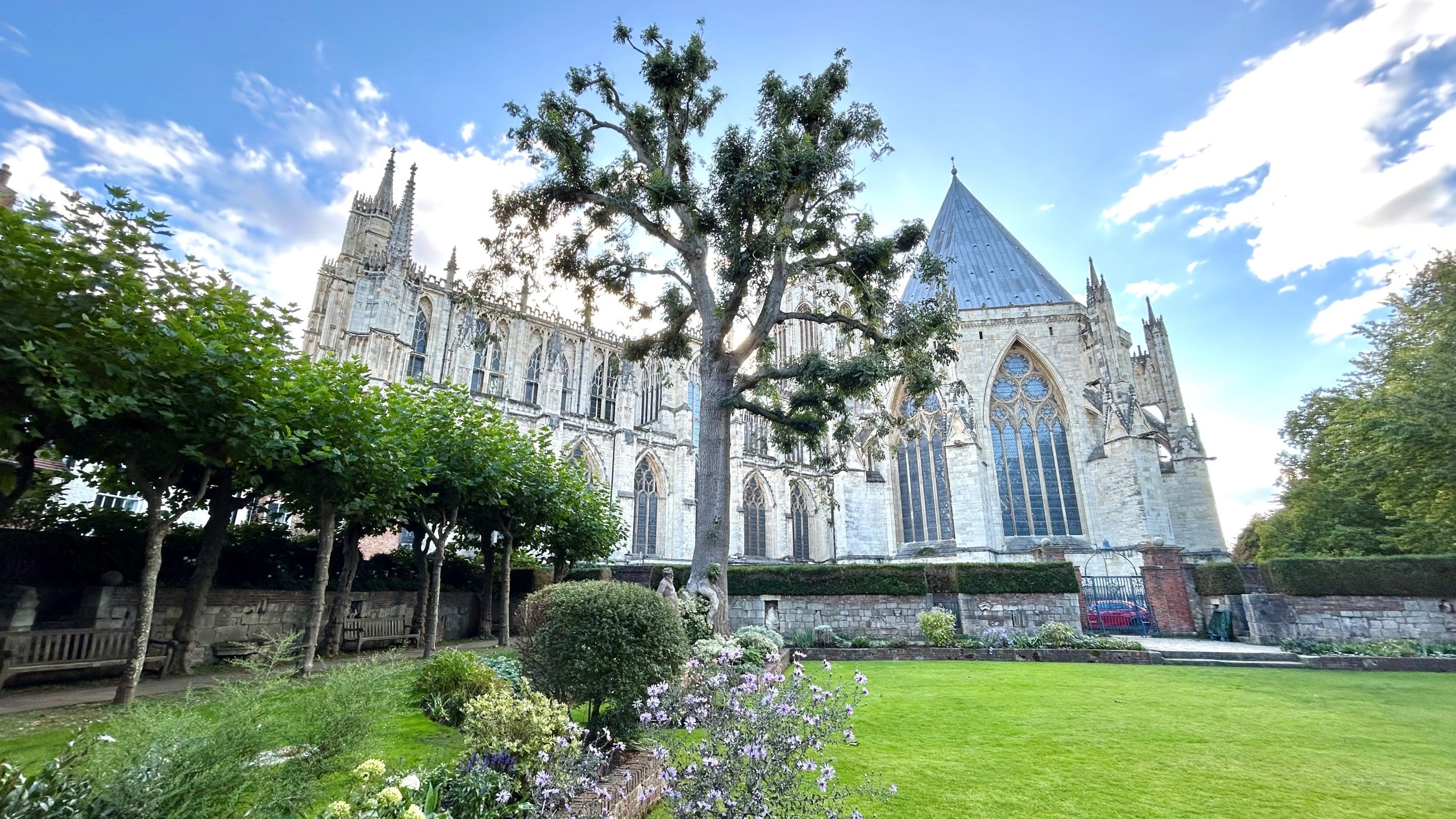 View across a garden with trees to a large Minster beyond