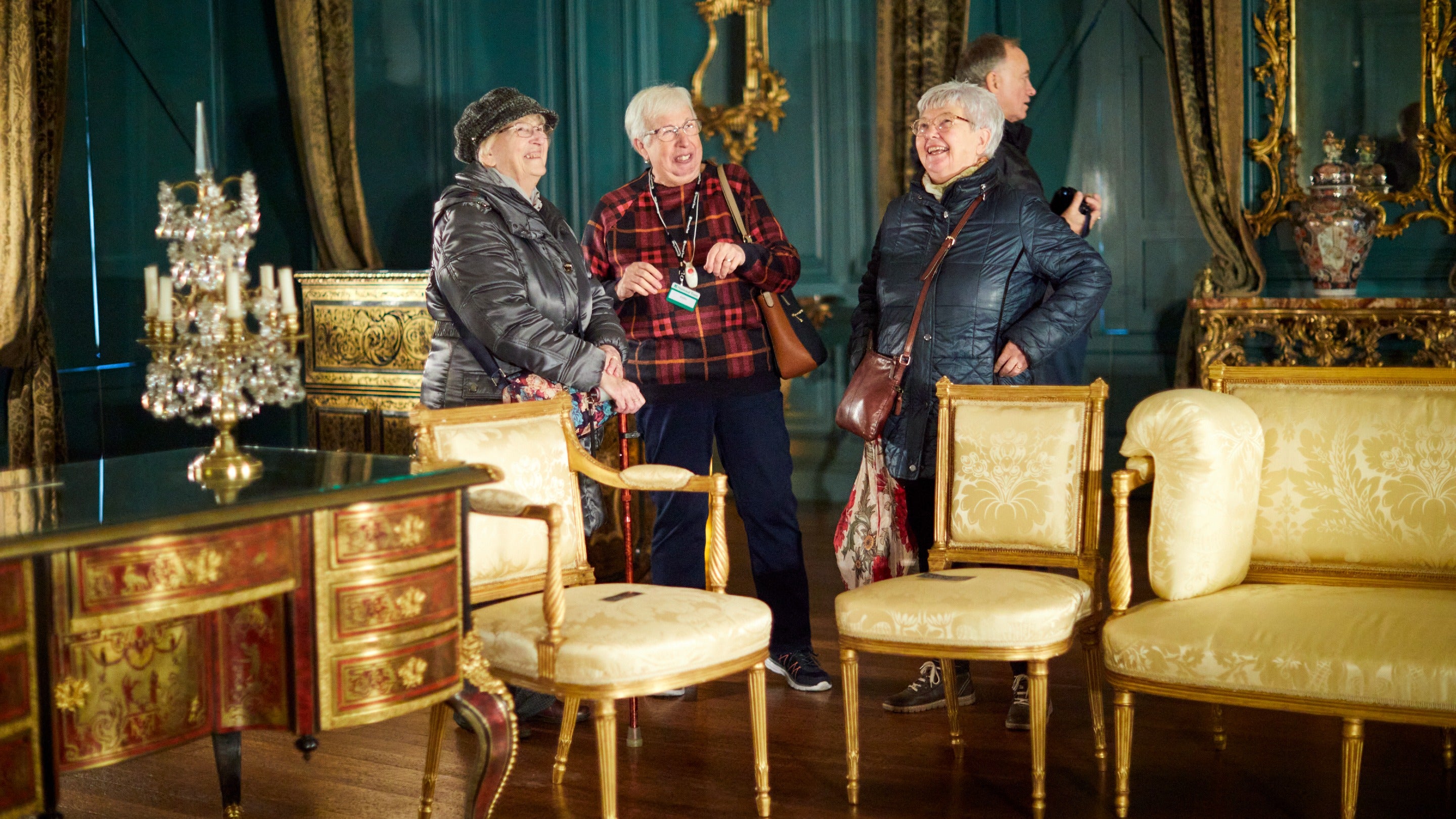 Three women laughing in a blue room with gold furniture