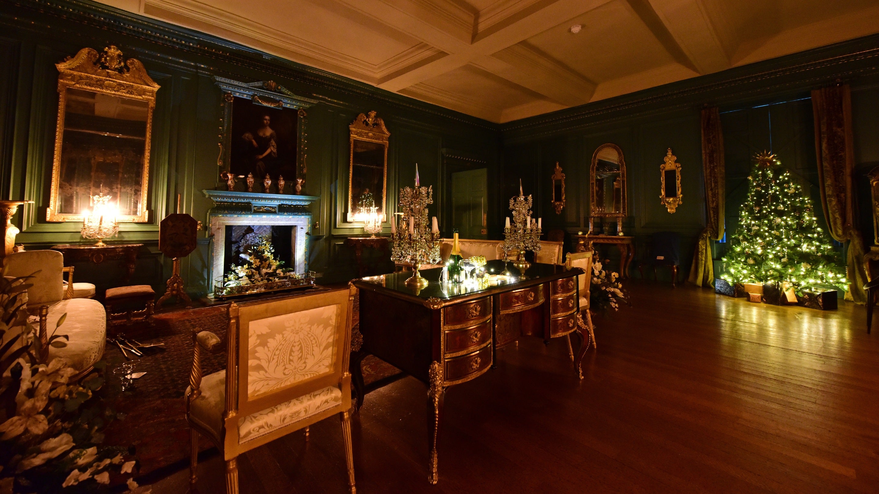 Dark historic room with gold furniture and frames and twinkly candelabras and Christmas tree
