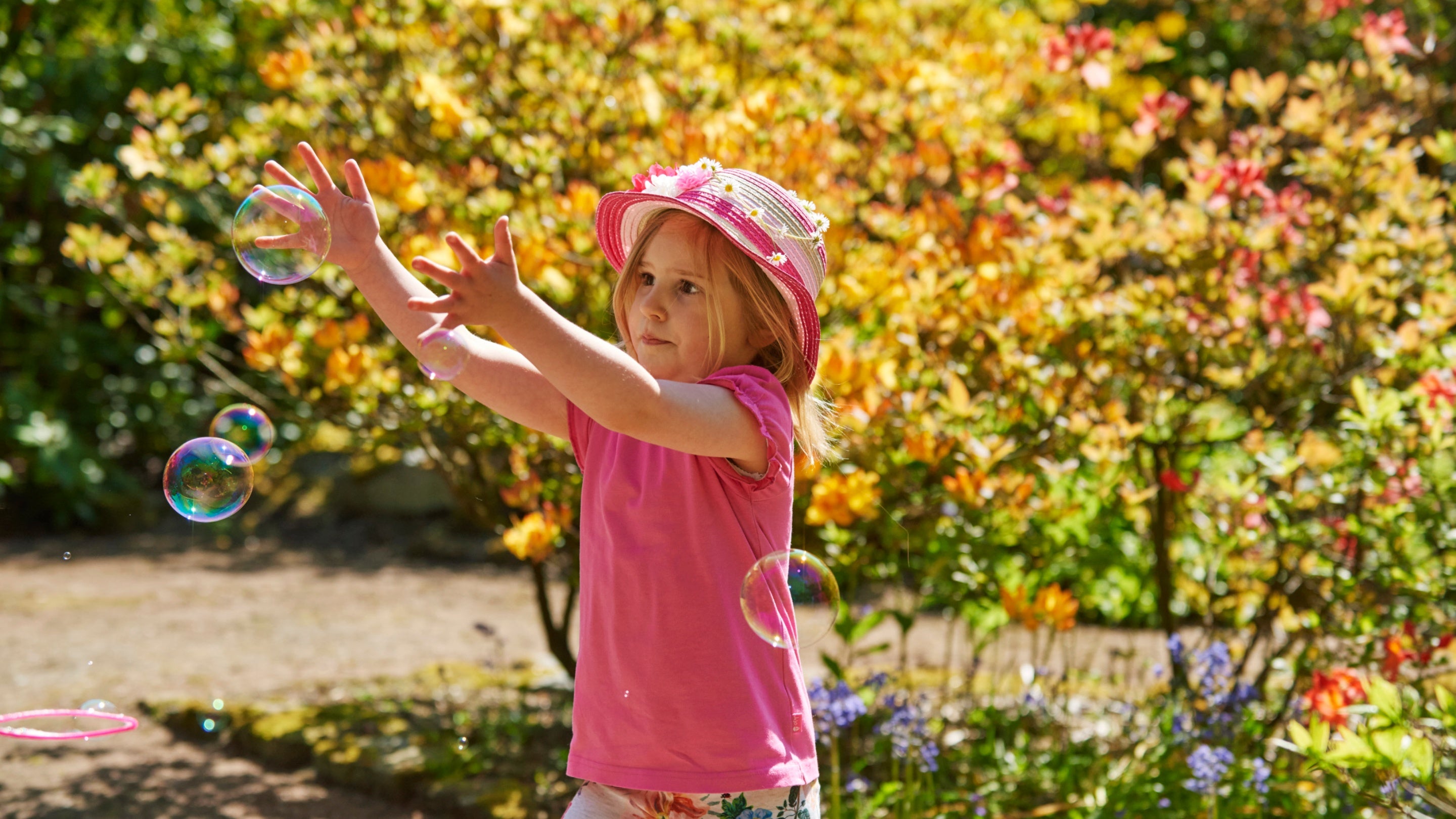 Girl in the Azalea Garden in May chasing bubbles with plants in the background at Wentworth Castle, South Yorkshire
