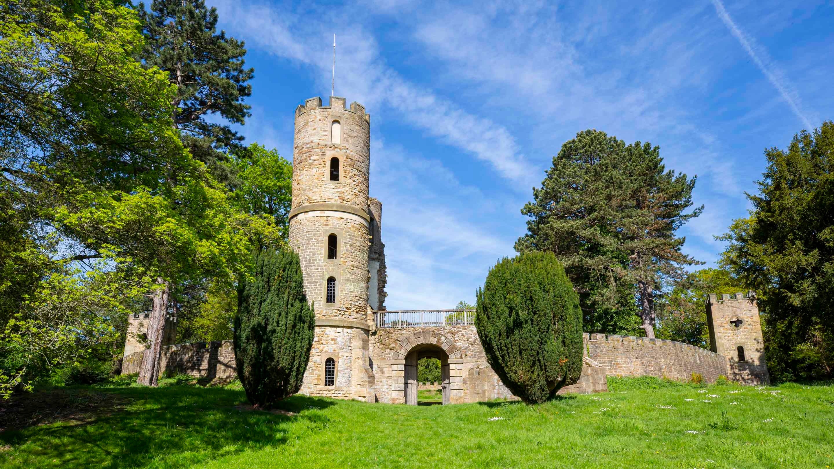 The exterior of Stainborough Castle, with a round tower and archway, at Wentworth Castle Gardens on a sunny day