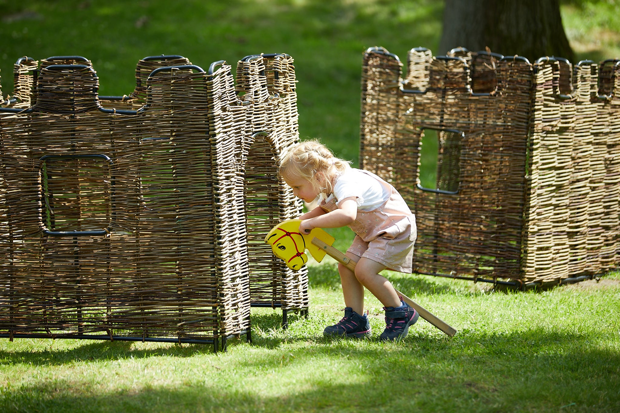 Child playing with a hobby horse and castles