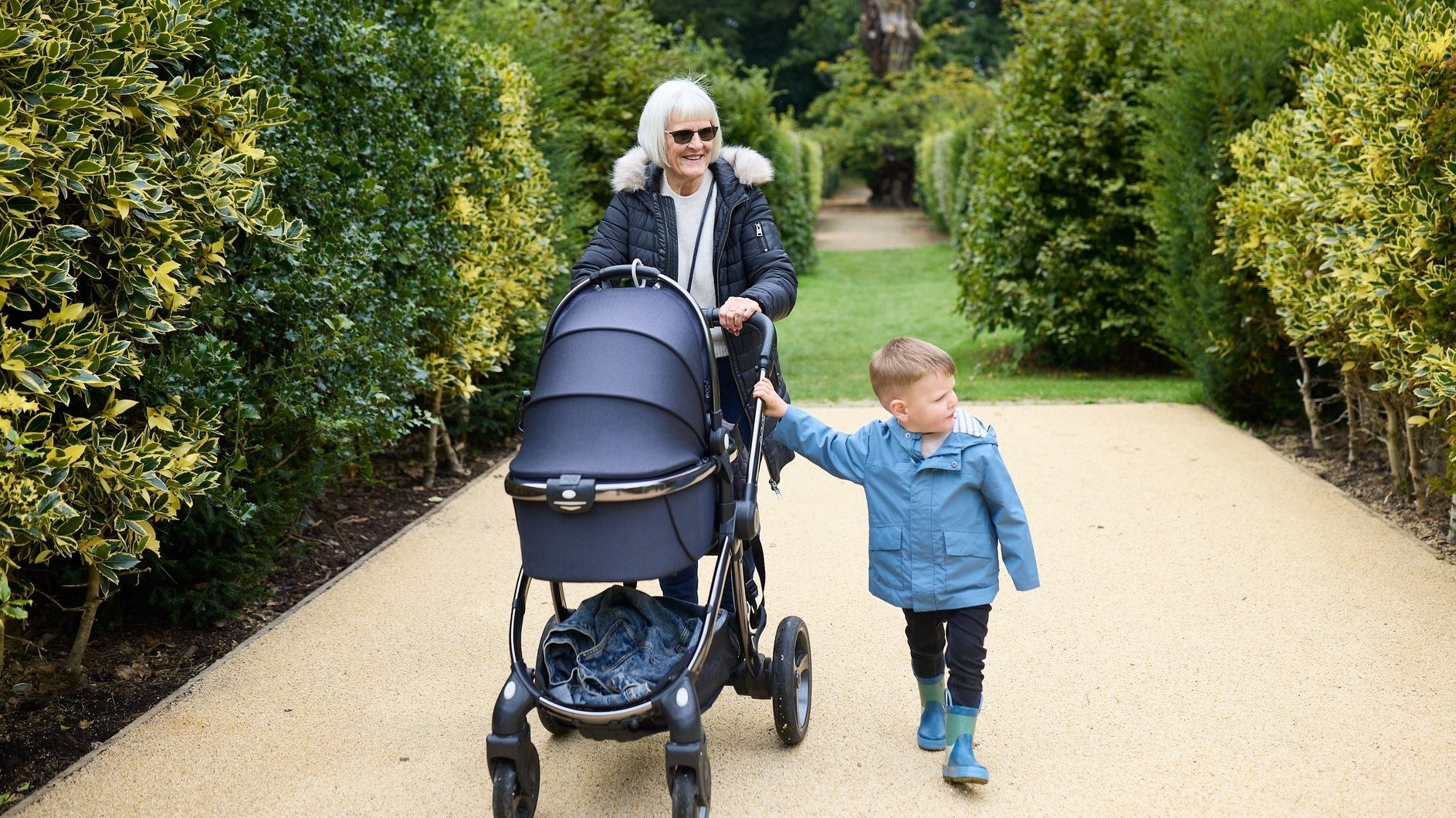Grandparent and grandchild walking along a path in the Union Jack Garden in early springtime.