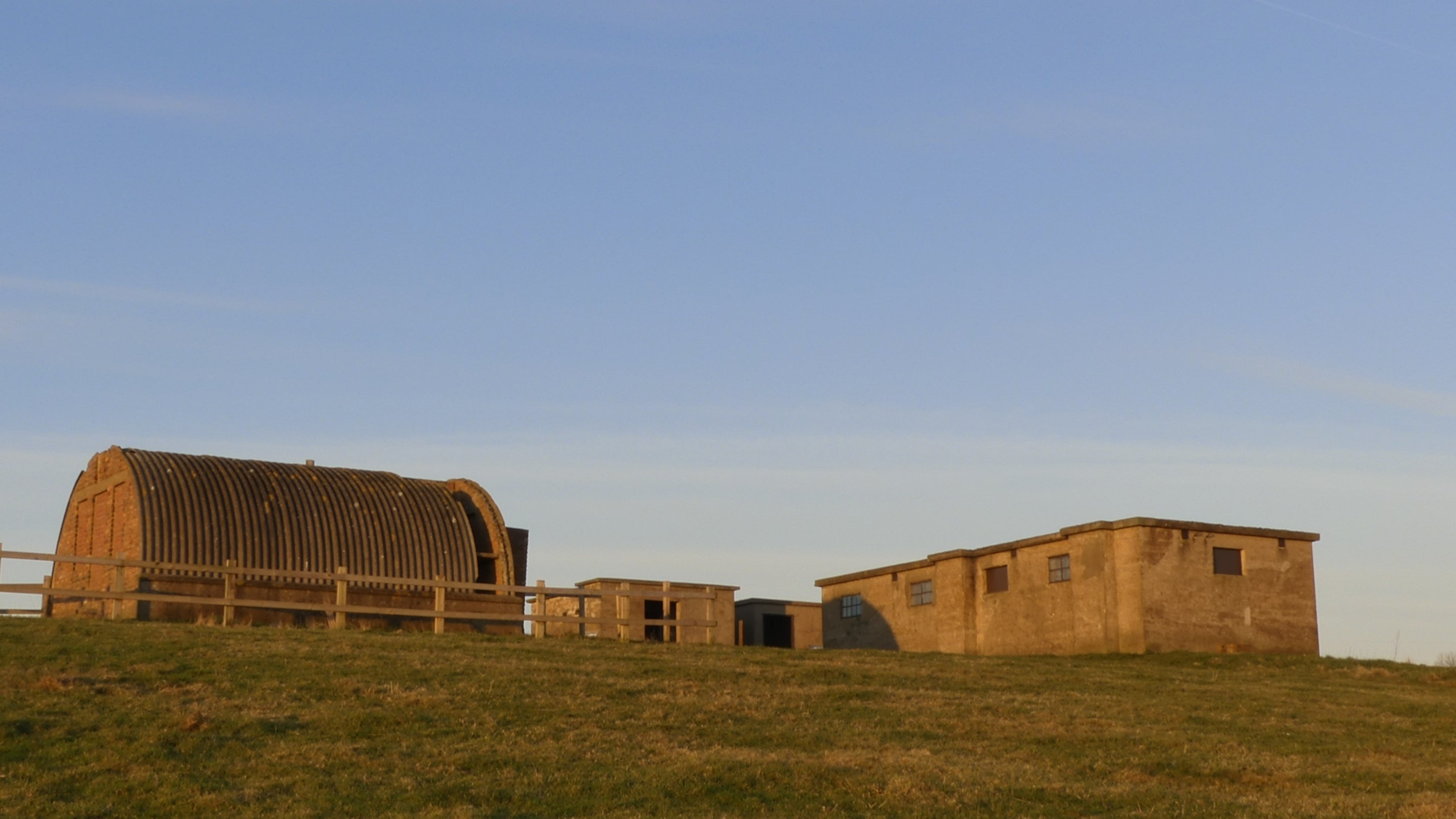 The empty buildings of Ravenscar Radar Station glowing 7in the orange light of sunrise