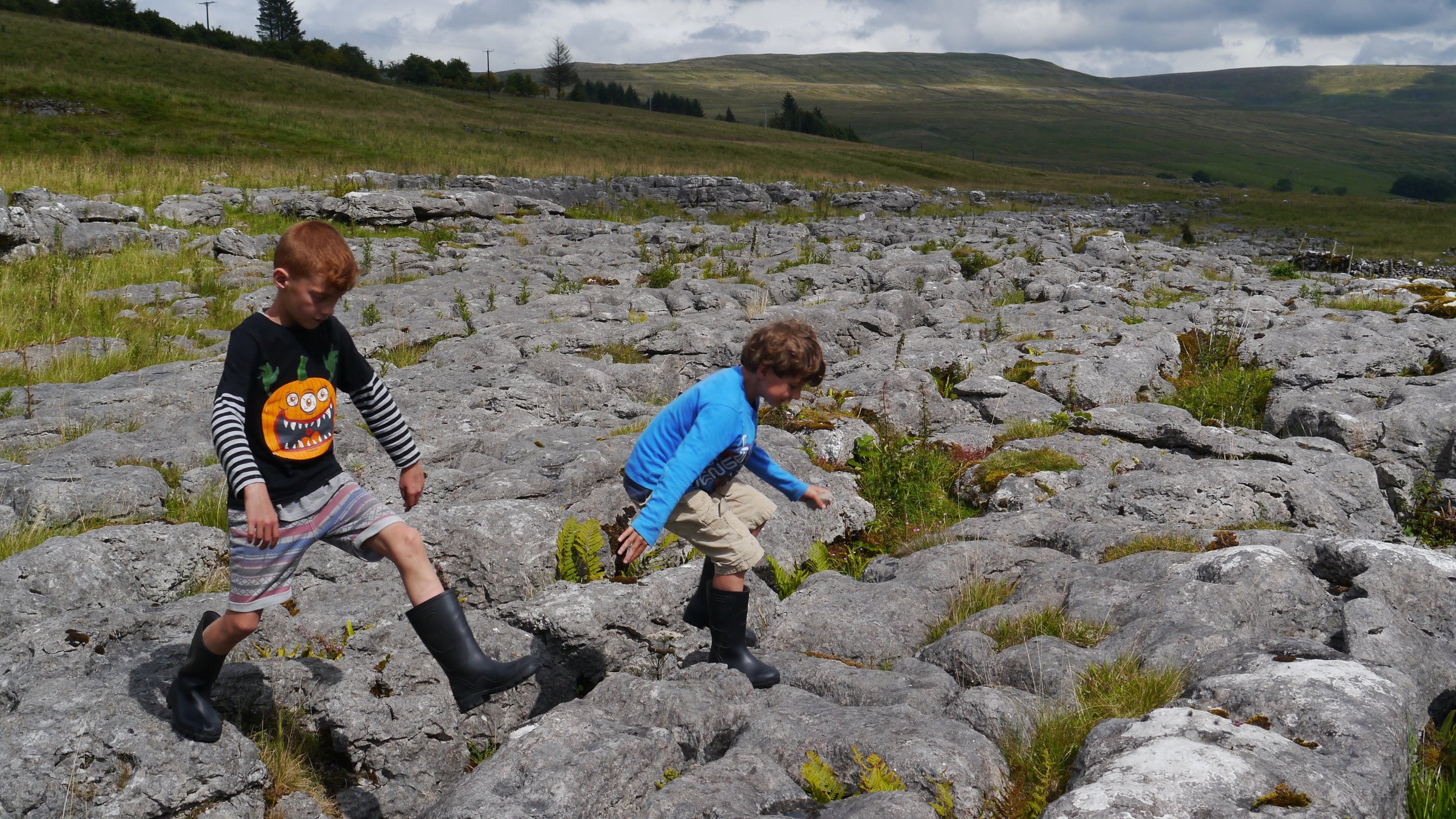 Children jumping on the limestone pavement at Upper Wharfedale, Yorkshire